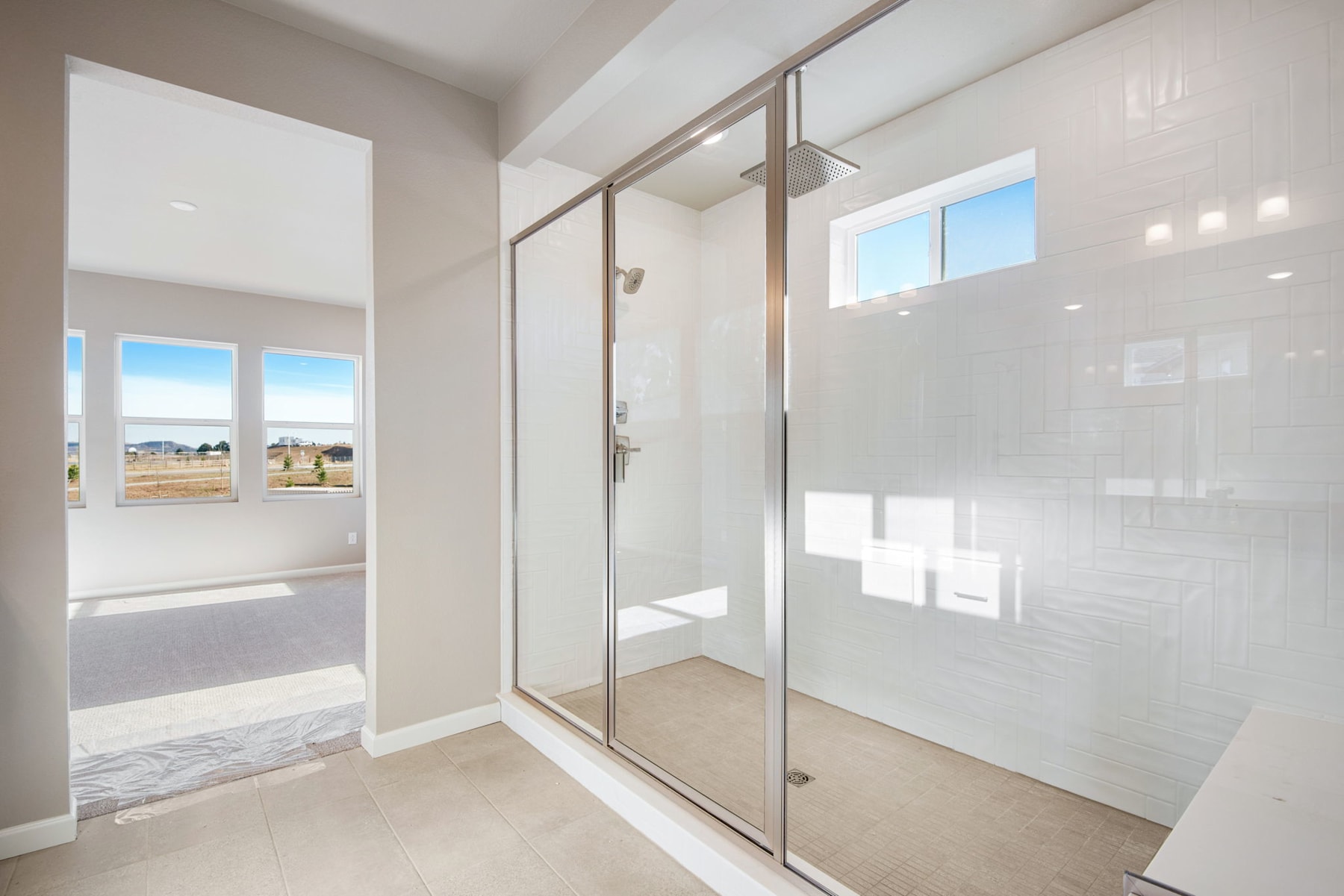 A bright and spacious entryway with a glass-paneled sliding door leading to an outdoor area, surrounded by clean white walls and a marble-like floor.