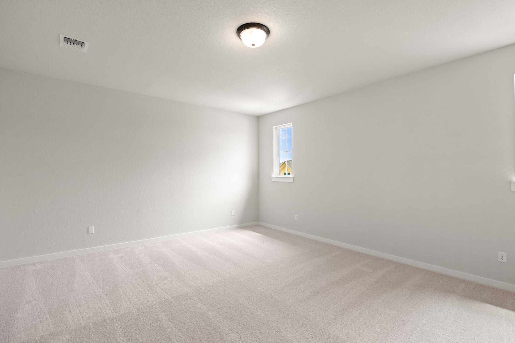 A bright, minimalist room with a single light fixture and a small window, featuring a hardwood floor and plain white walls.