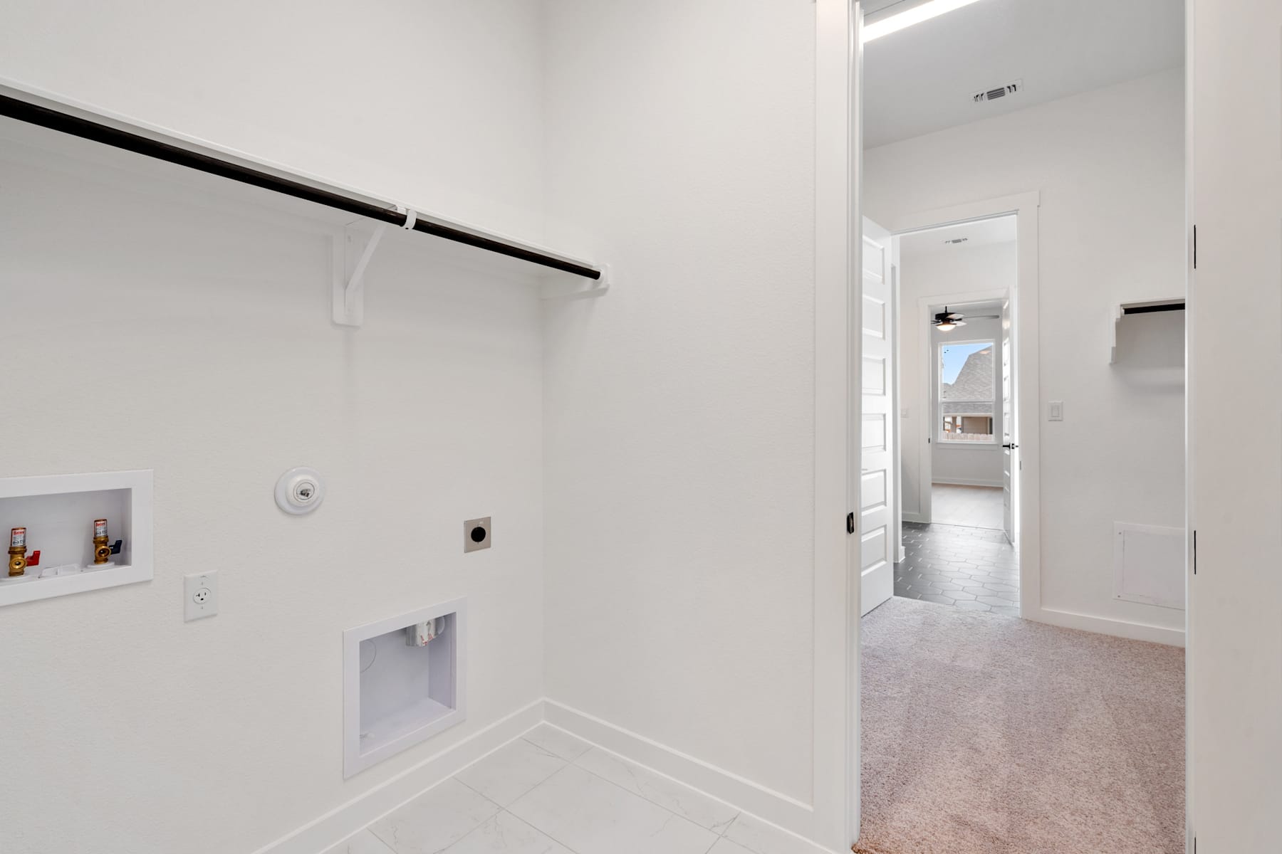 A white-walled room with a closet rod and a doorway leading to another room in the background.