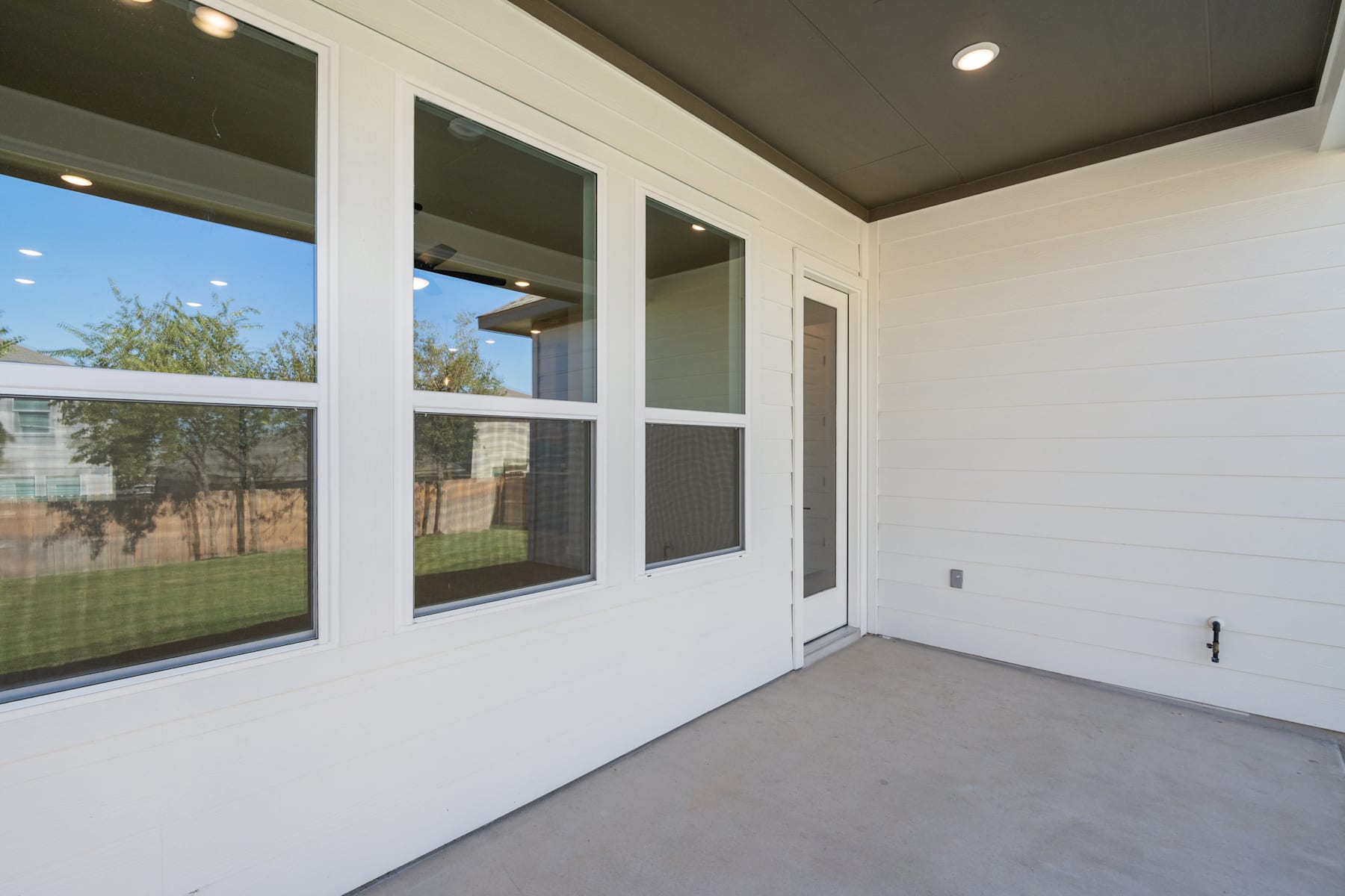 A spacious, well-lit room with large windows overlooking a grassy outdoor area, featuring a clean and minimalist interior design.