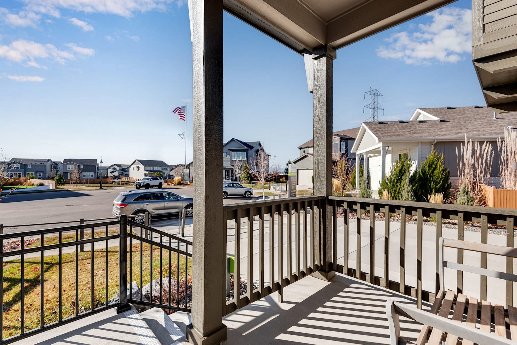A residential neighborhood with houses, a porch, and a street visible in the background, with a clear blue sky overhead.