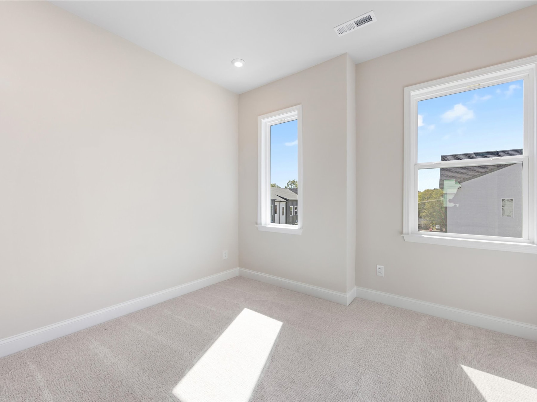 A bright and spacious room with large windows, neutral-colored walls, and a tiled floor, creating a clean and modern atmosphere.