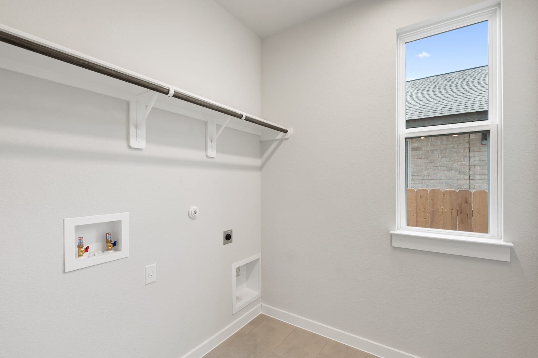 The image shows a clean, well-lit closet space with a window, a clothing rod, and electrical outlets on the wall.
