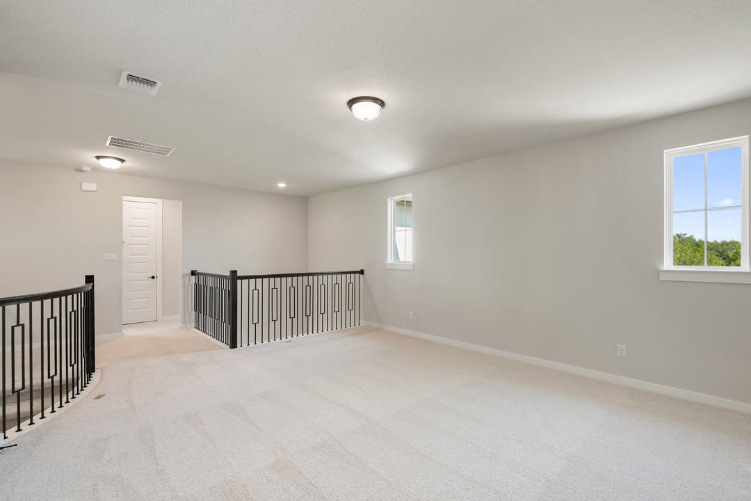 A spacious, well-lit room with a wooden railing and a window overlooking the outdoors.