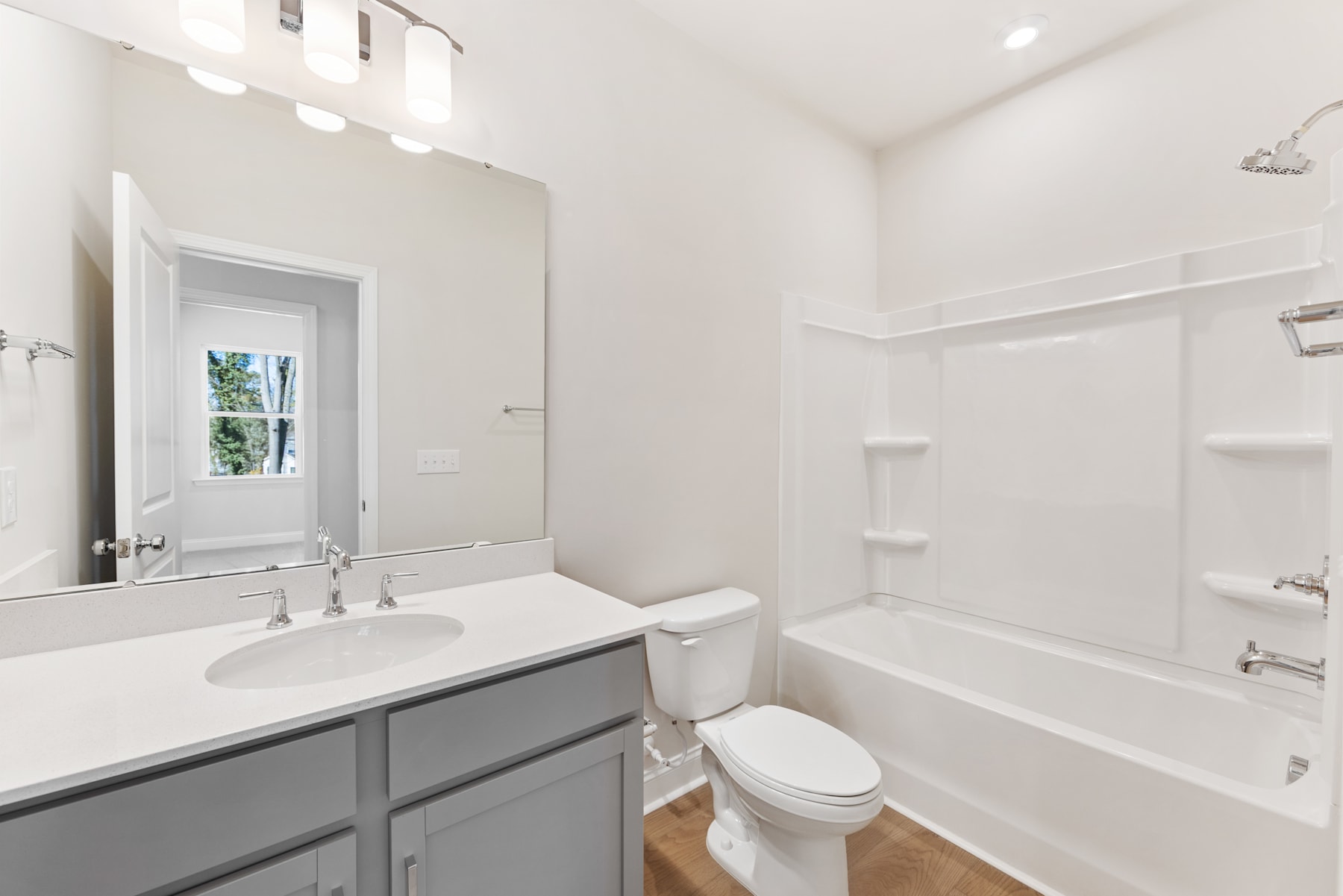 A modern, well-lit bathroom with a vanity, toilet, and bathtub, featuring a neutral color scheme and clean, minimalist design.