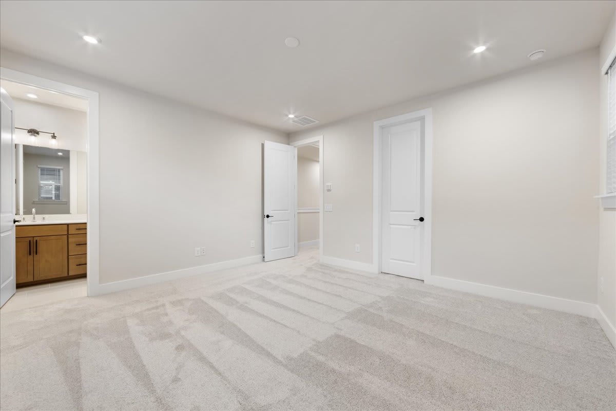A spacious, minimalist room with white walls, wooden cabinets, and a hardwood floor with a striped pattern.