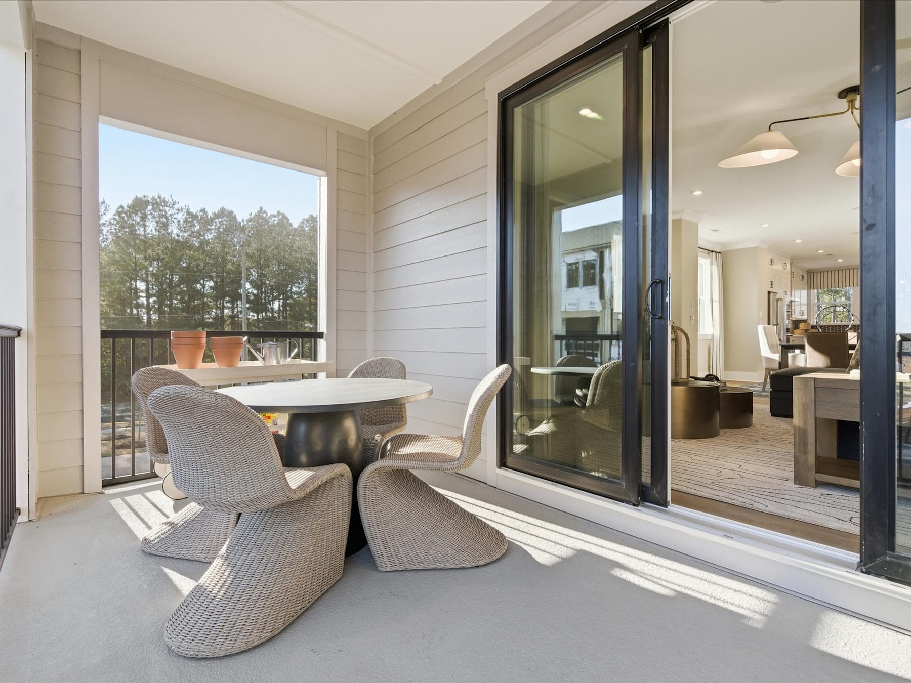 A cozy outdoor seating area with comfortable chairs and a table, surrounded by large windows that offer a view of the trees and natural landscape beyond.