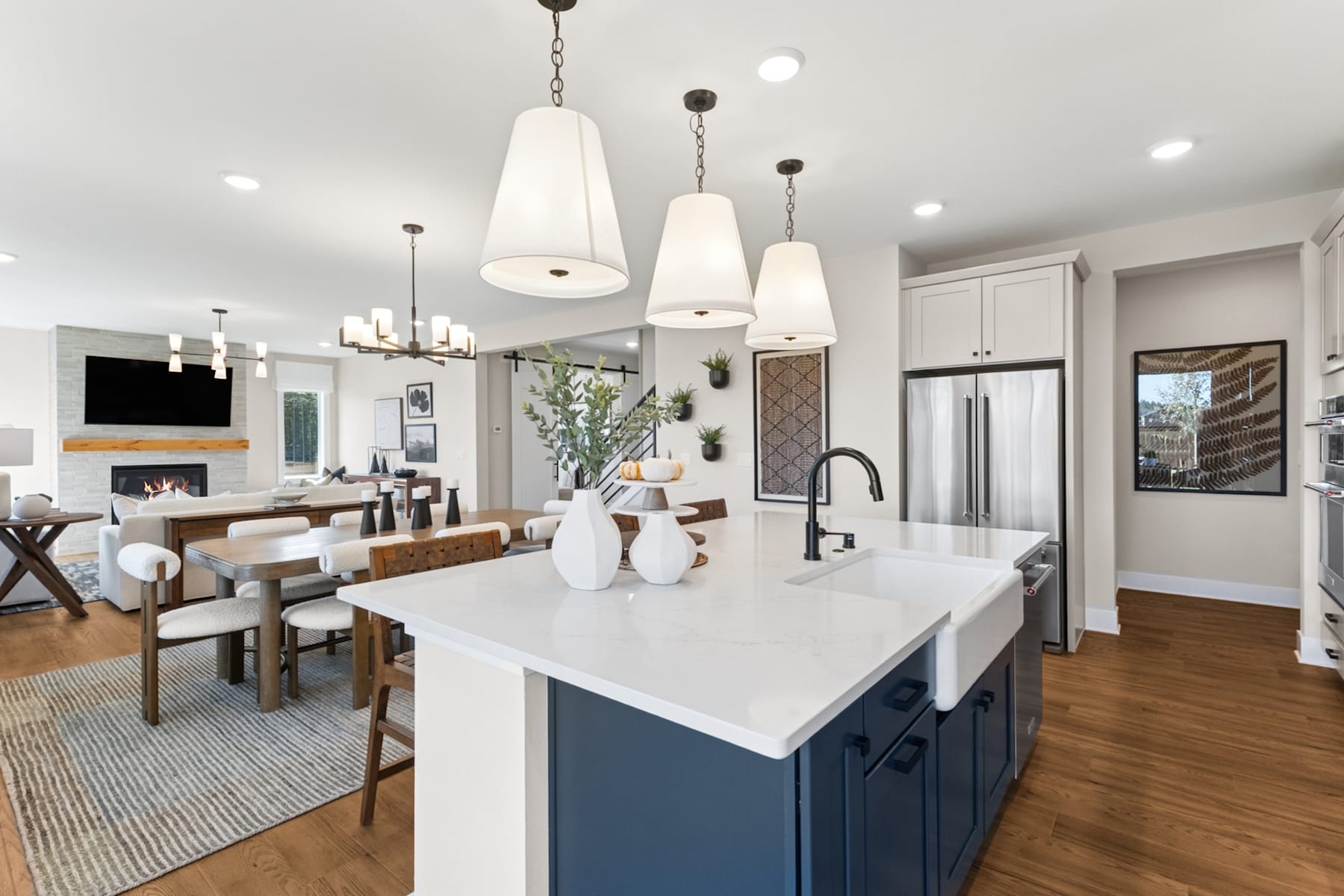 A modern and stylish kitchen with a large white island, pendant lights, and a dining area in the background.