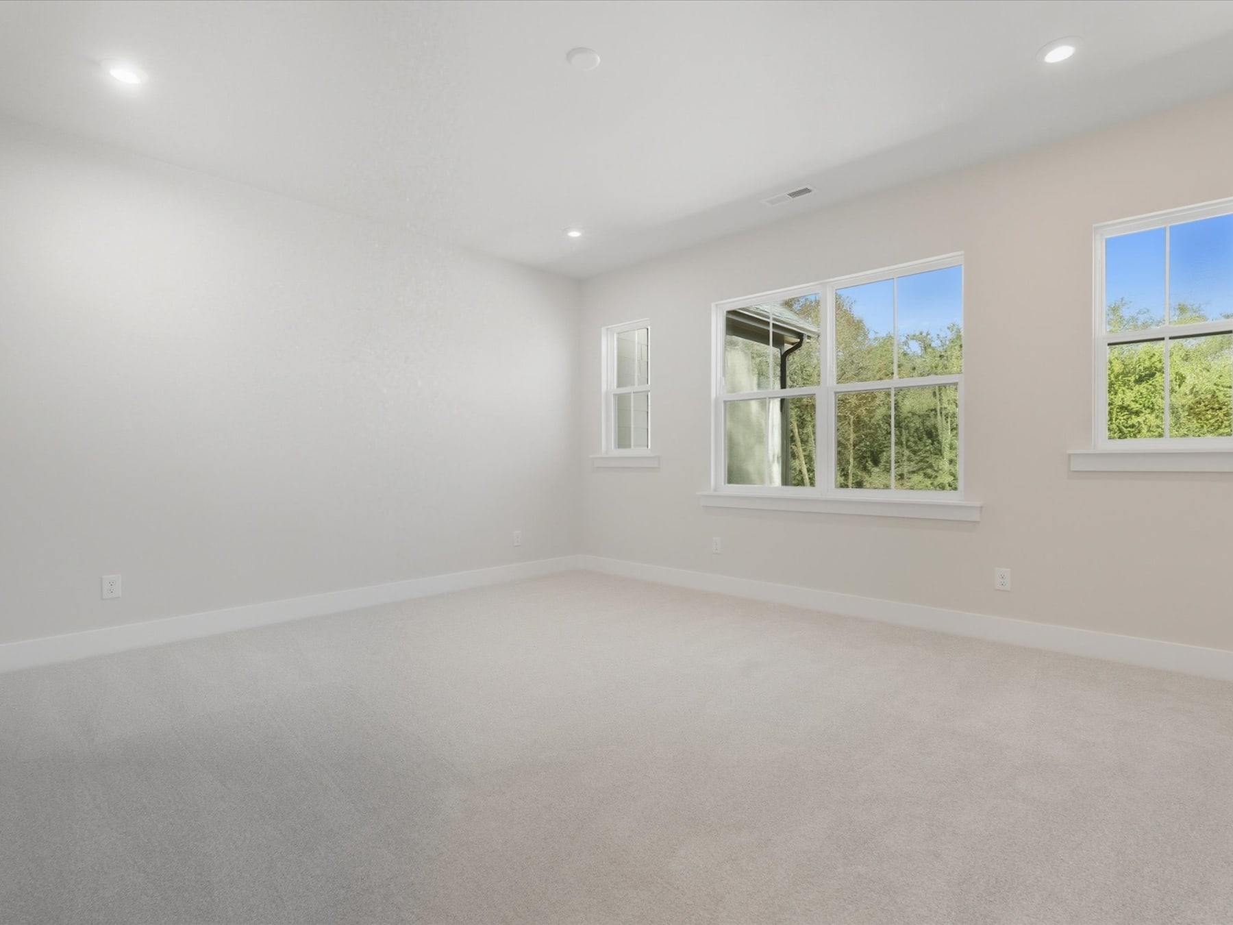 A bright, spacious room with large windows overlooking a lush, green outdoor landscape.