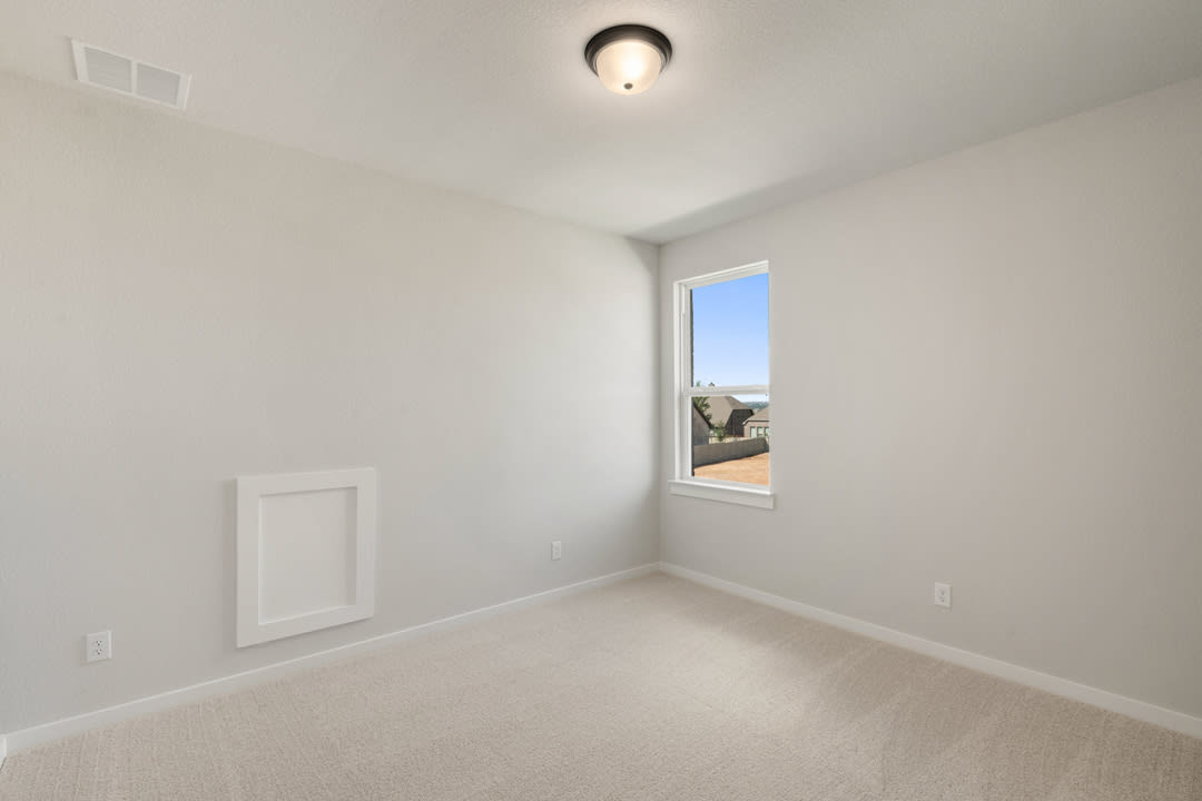 A simple, minimalist bedroom with a window overlooking an outdoor area, featuring a clean and bright interior design.