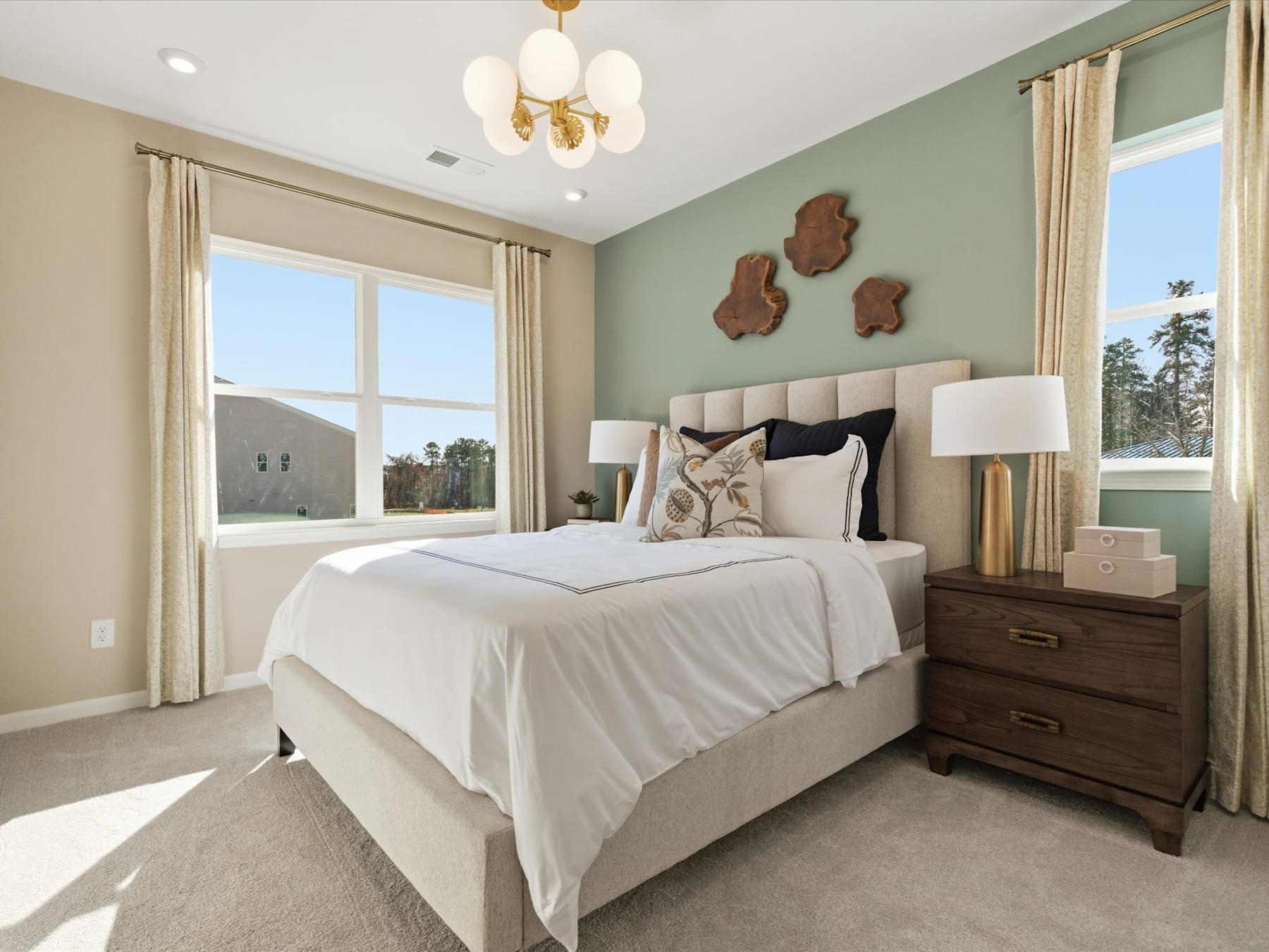 A cozy and inviting bedroom with a large bed, wooden furniture, and decorative wall accents, set against a backdrop of large windows overlooking a scenic outdoor landscape.
