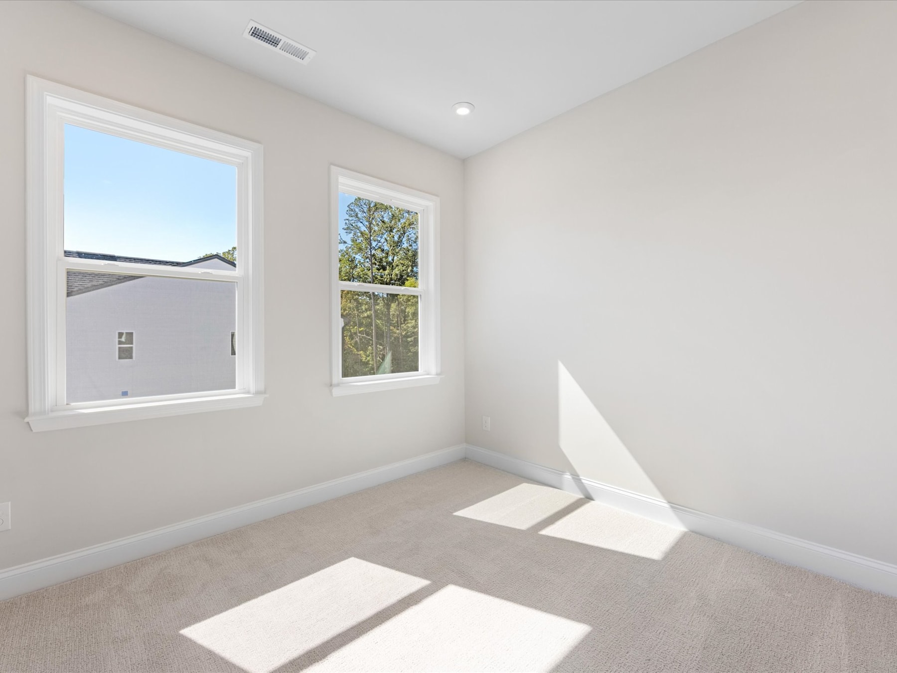 A bright and airy room with large windows overlooking a tree-lined outdoor scene, featuring a neutral color palette and clean, minimalist design.