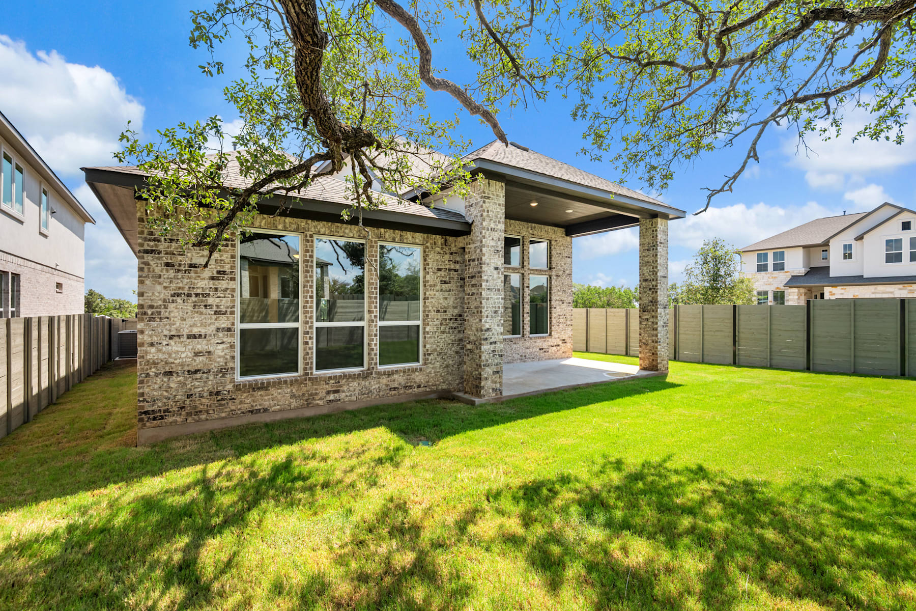 A well-maintained residential property with a brick exterior, surrounded by lush greenery and a clear blue sky in the background.