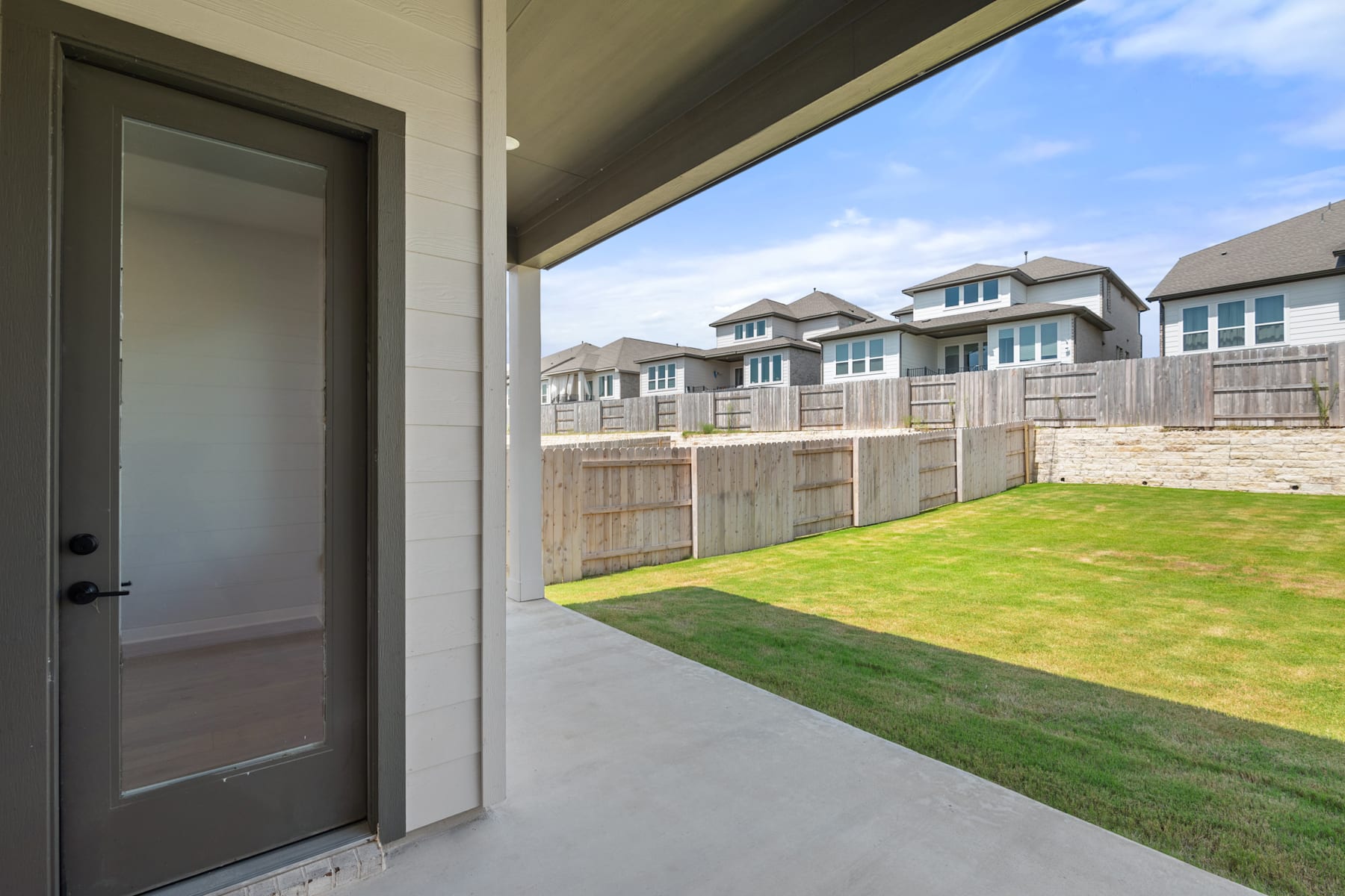 A modern residential neighborhood with a well-manicured lawn and a glass-paneled door leading to the exterior.