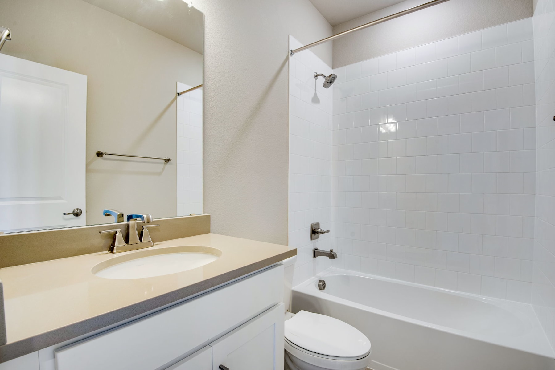 A modern bathroom with a white vanity, a large mirror, and a bathtub with a shower curtain.
