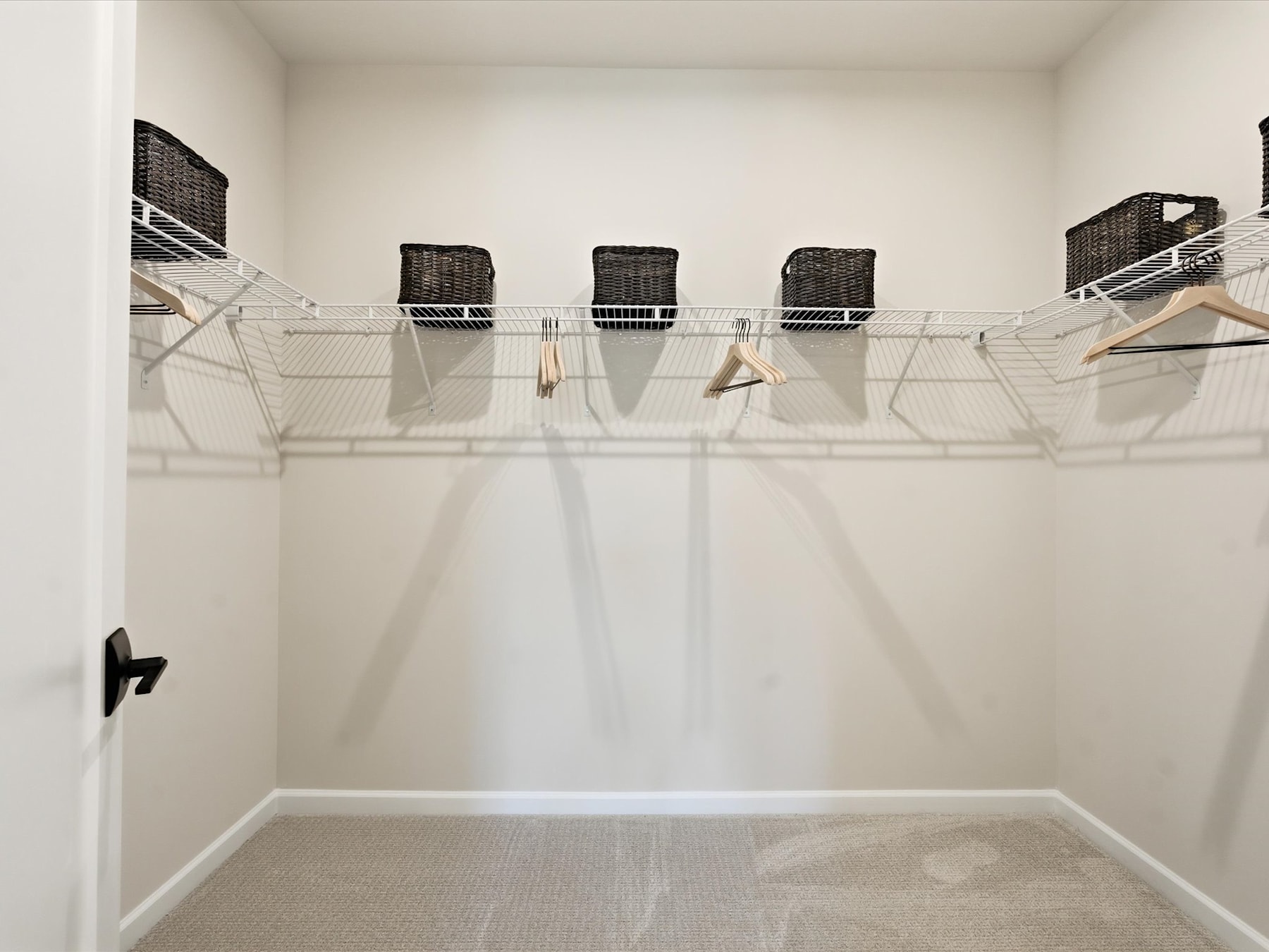 A minimalist closet space with wire shelves and hanging rods, providing ample storage and organization for clothing and accessories.