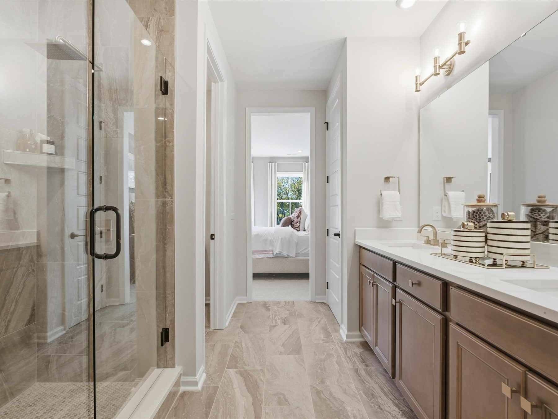 A spacious and well-lit bathroom with a vanity, mirror, and a view of an adjacent room through an open doorway.