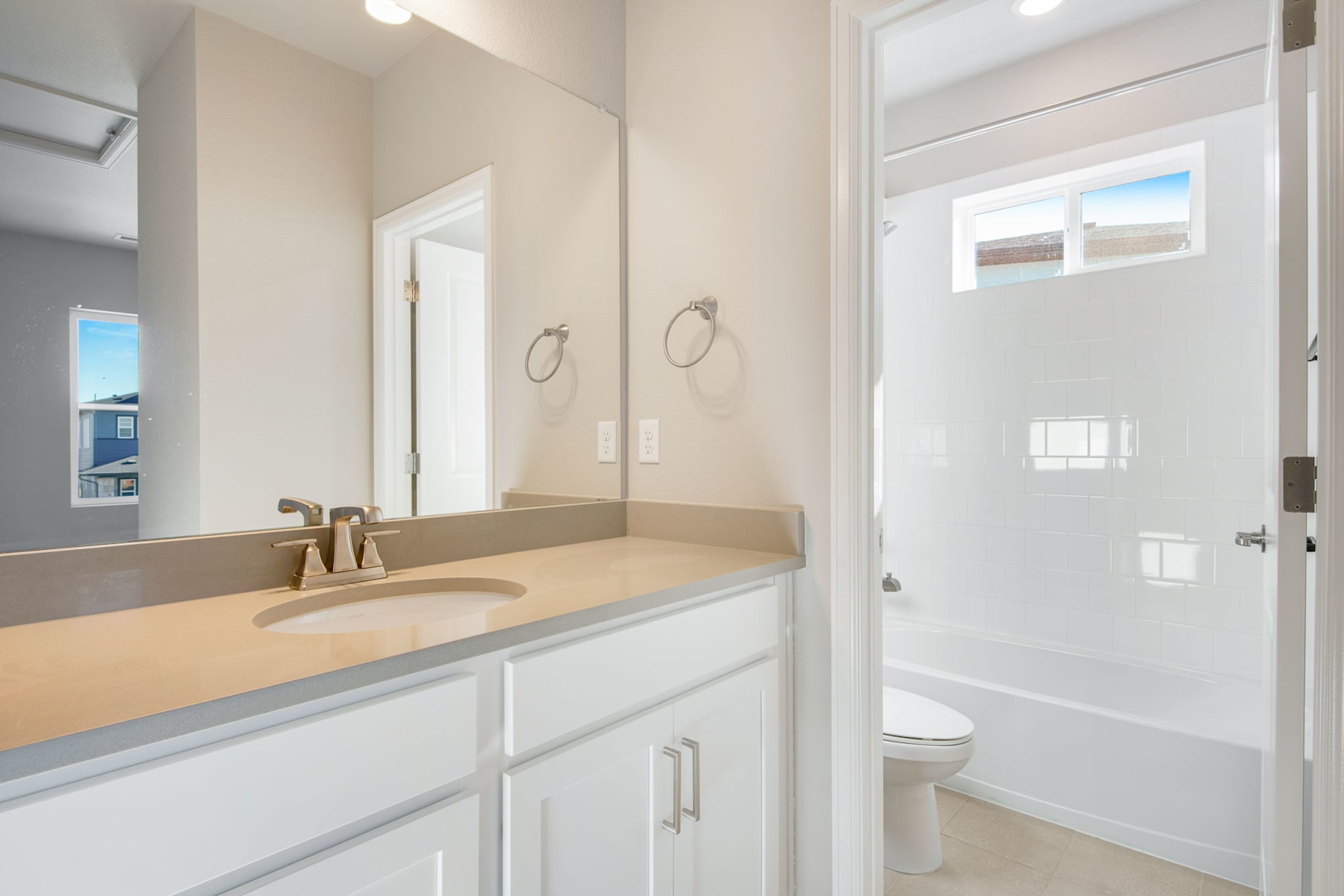 A modern, well-lit bathroom with a white vanity, a large mirror, and a shower enclosure in the background.