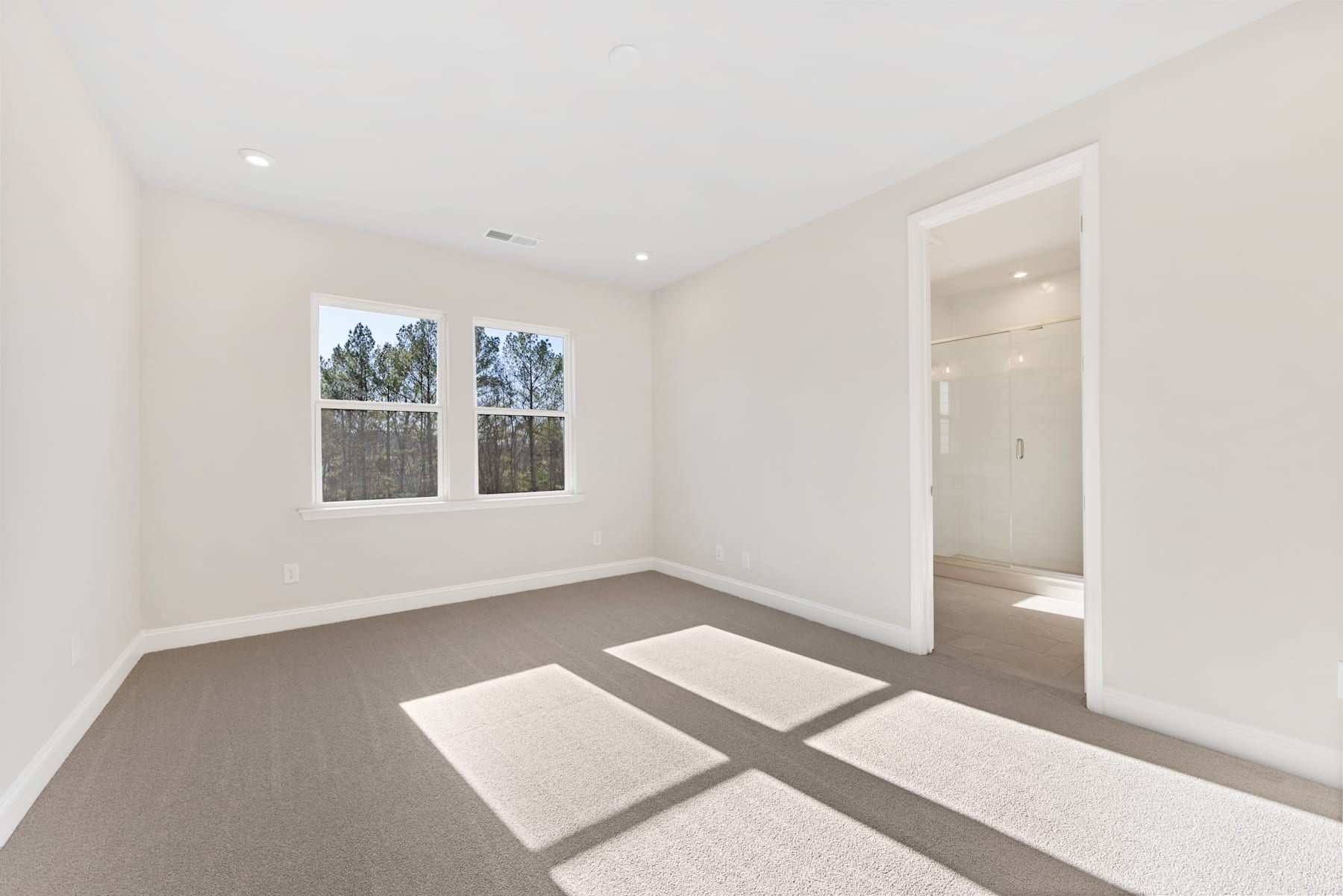 A spacious, well-lit room with large windows, a neutral color palette, and a hardwood floor creating a clean, minimalist aesthetic.