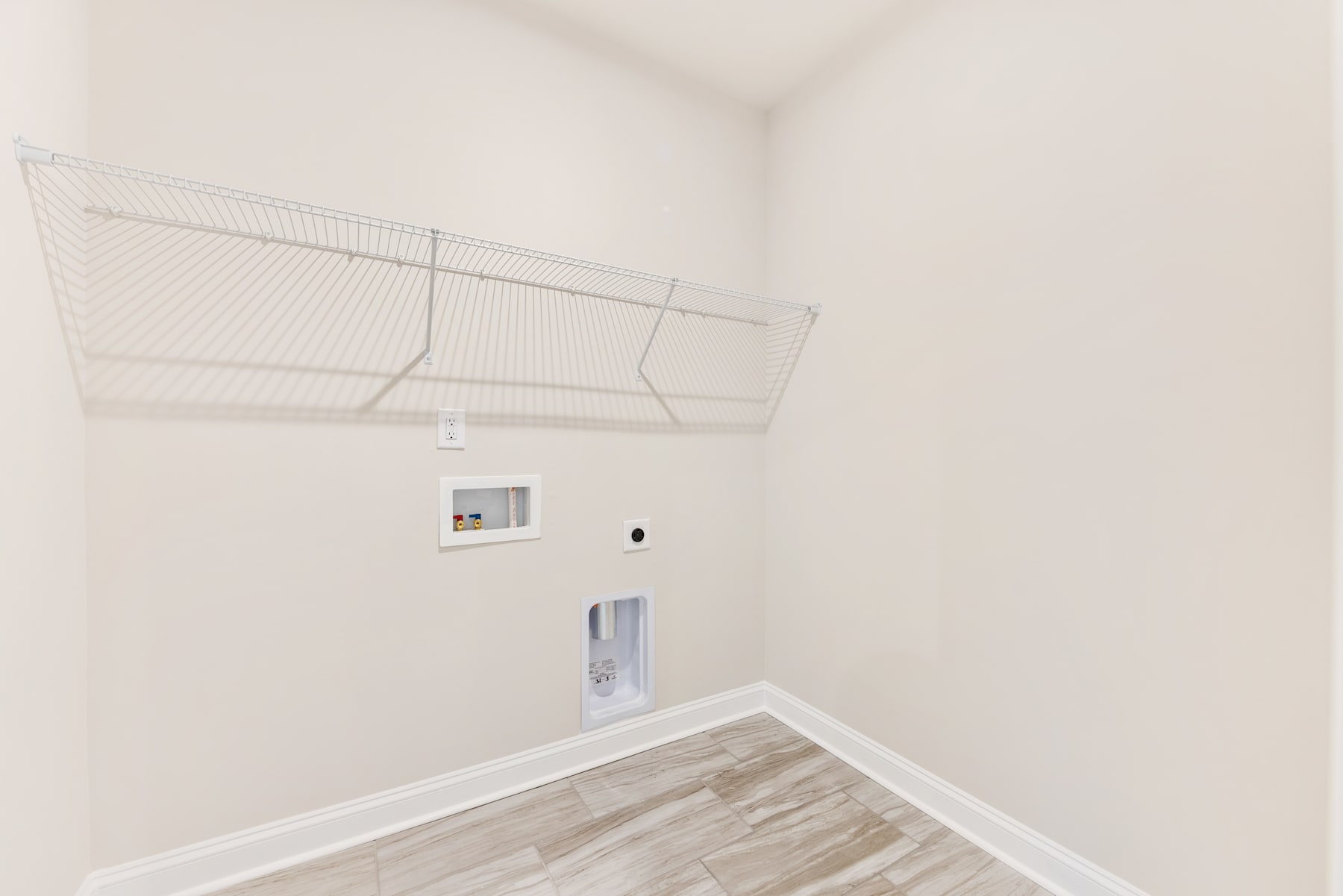 A small, well-lit room with a white wall and a wire mesh structure attached to the ceiling, along with a white electrical box on the wall.