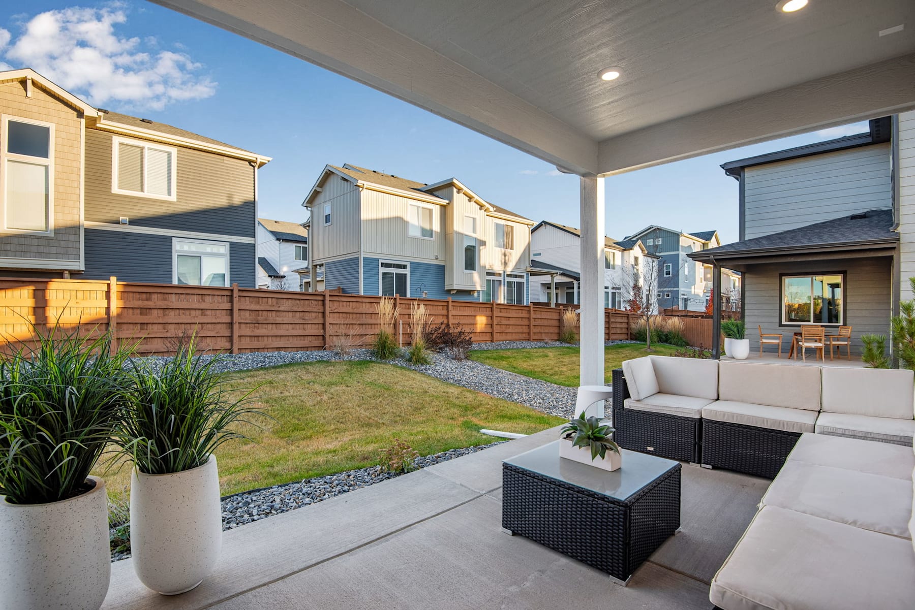 A cozy outdoor seating area with a well-manicured lawn and surrounding townhouses in the background, creating a pleasant and inviting residential setting.