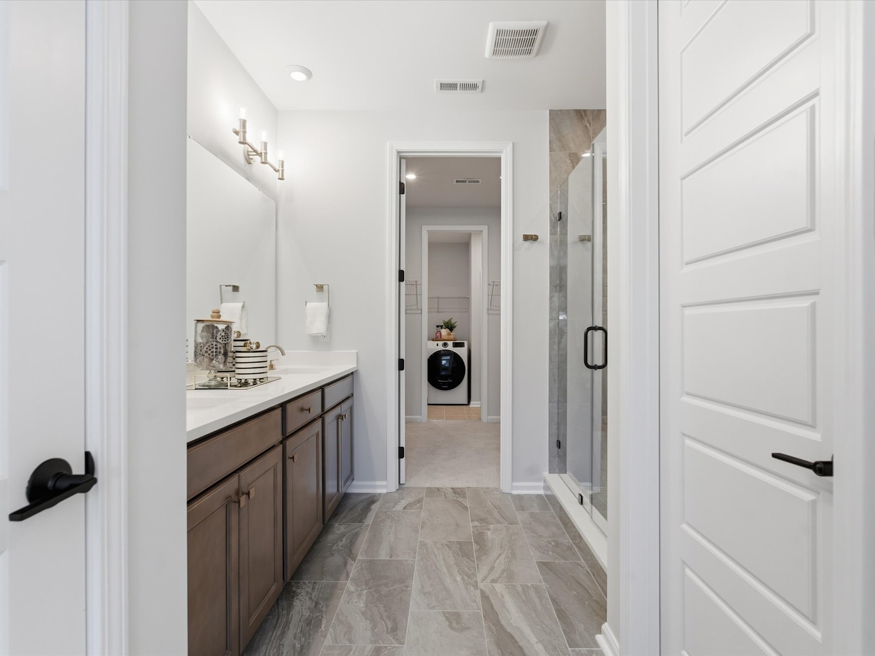 A well-lit hallway with a vanity cabinet and a doorway leading to another room, featuring a neutral color scheme and modern design elements.