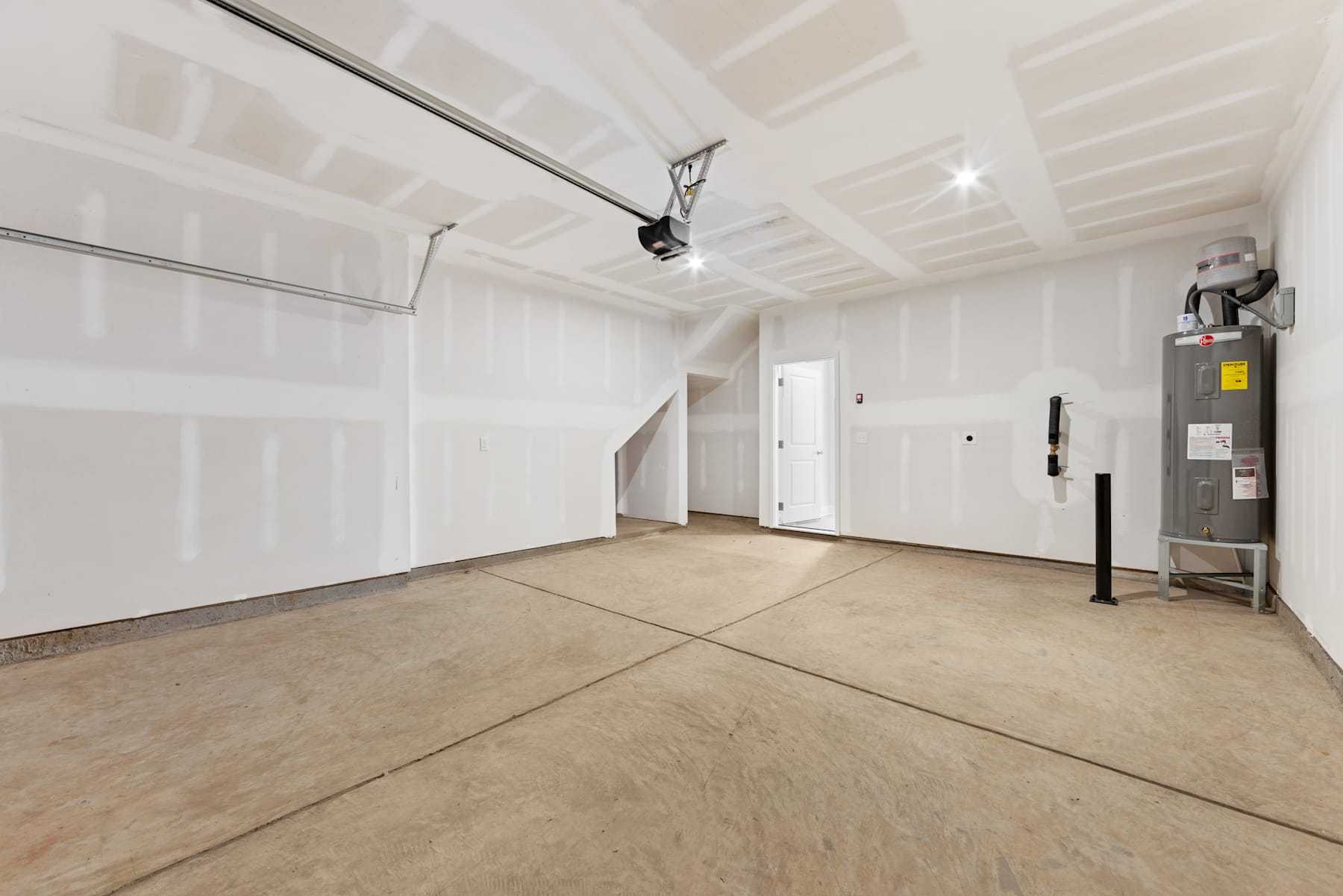 A spacious, unfinished room with a concrete floor, white walls, and a track lighting system installed on the ceiling.
