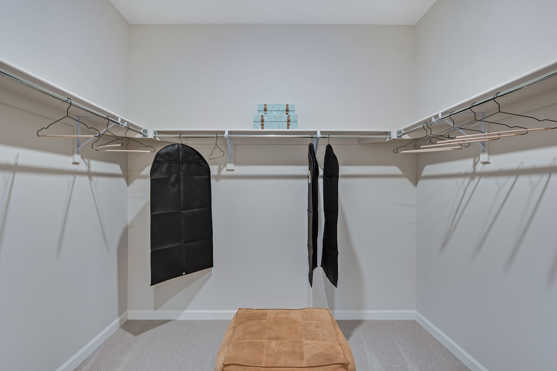 A well-organized closet with hanging rods, shelves, and a bench, providing ample storage and organization space.