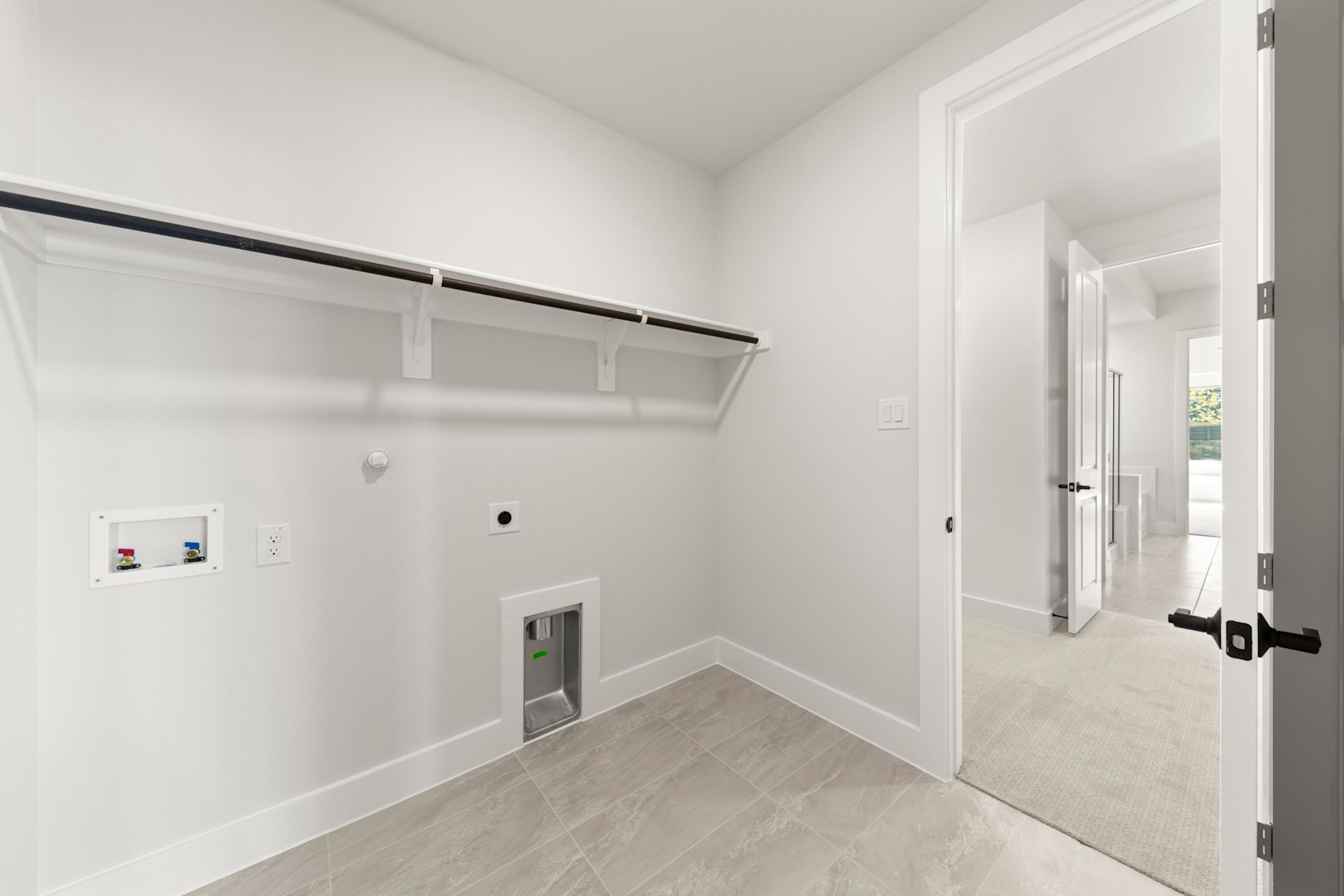 A spacious, well-lit closet with white walls, a built-in shelf system, and a doorway leading to another room.