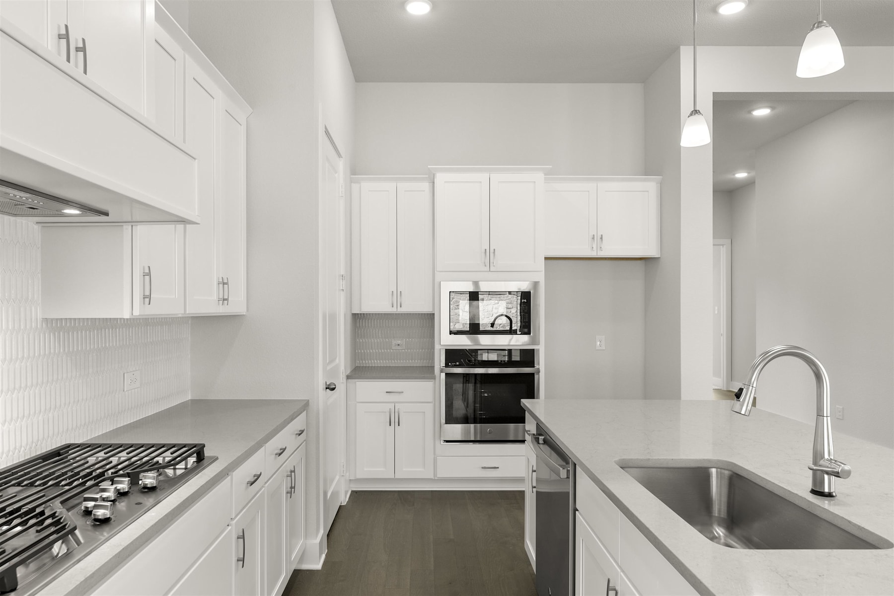 A modern, minimalist kitchen with white cabinets, stainless steel appliances, and a large sink in the foreground.