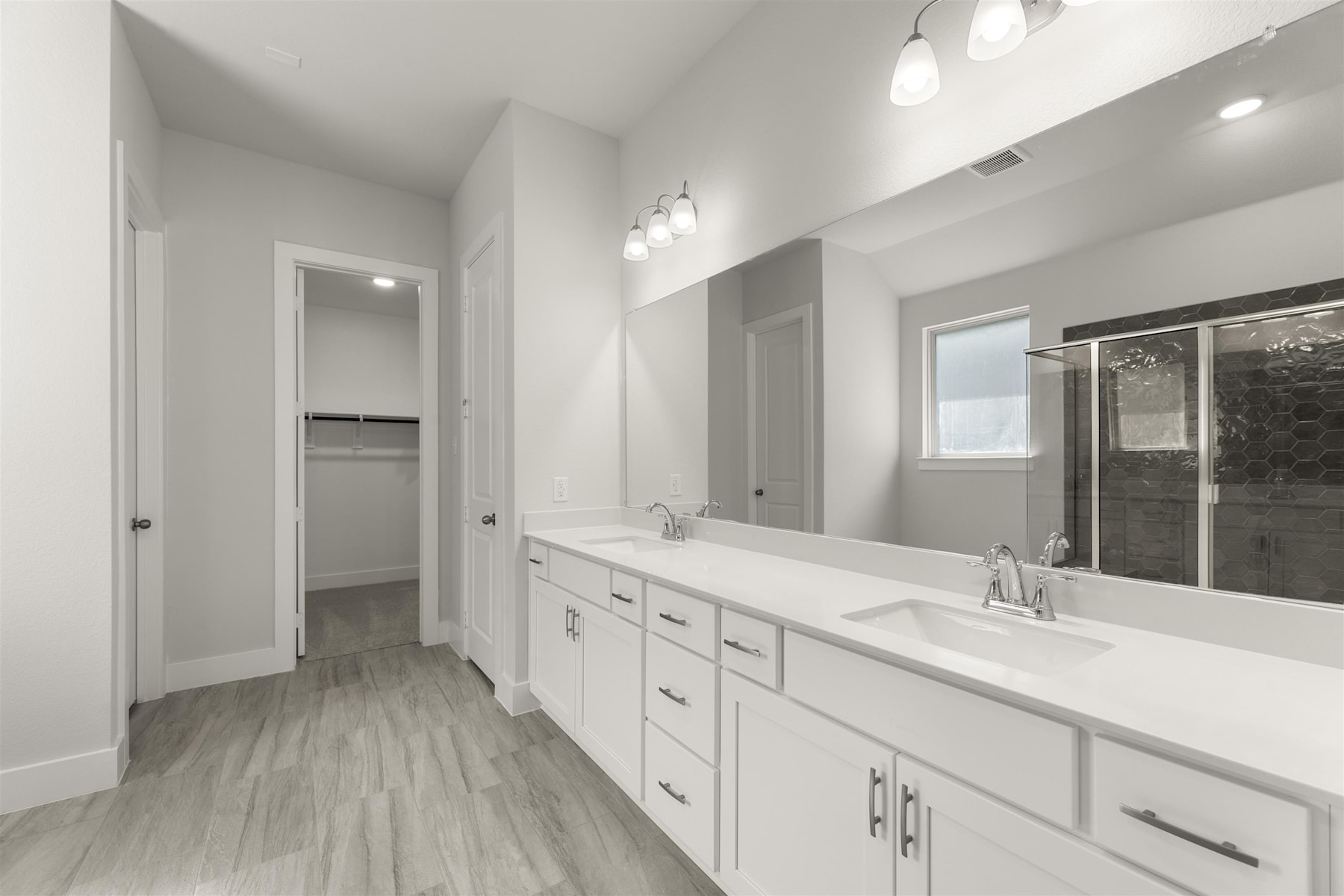 A spacious and modern bathroom with white cabinets, a large vanity, and a tiled floor.