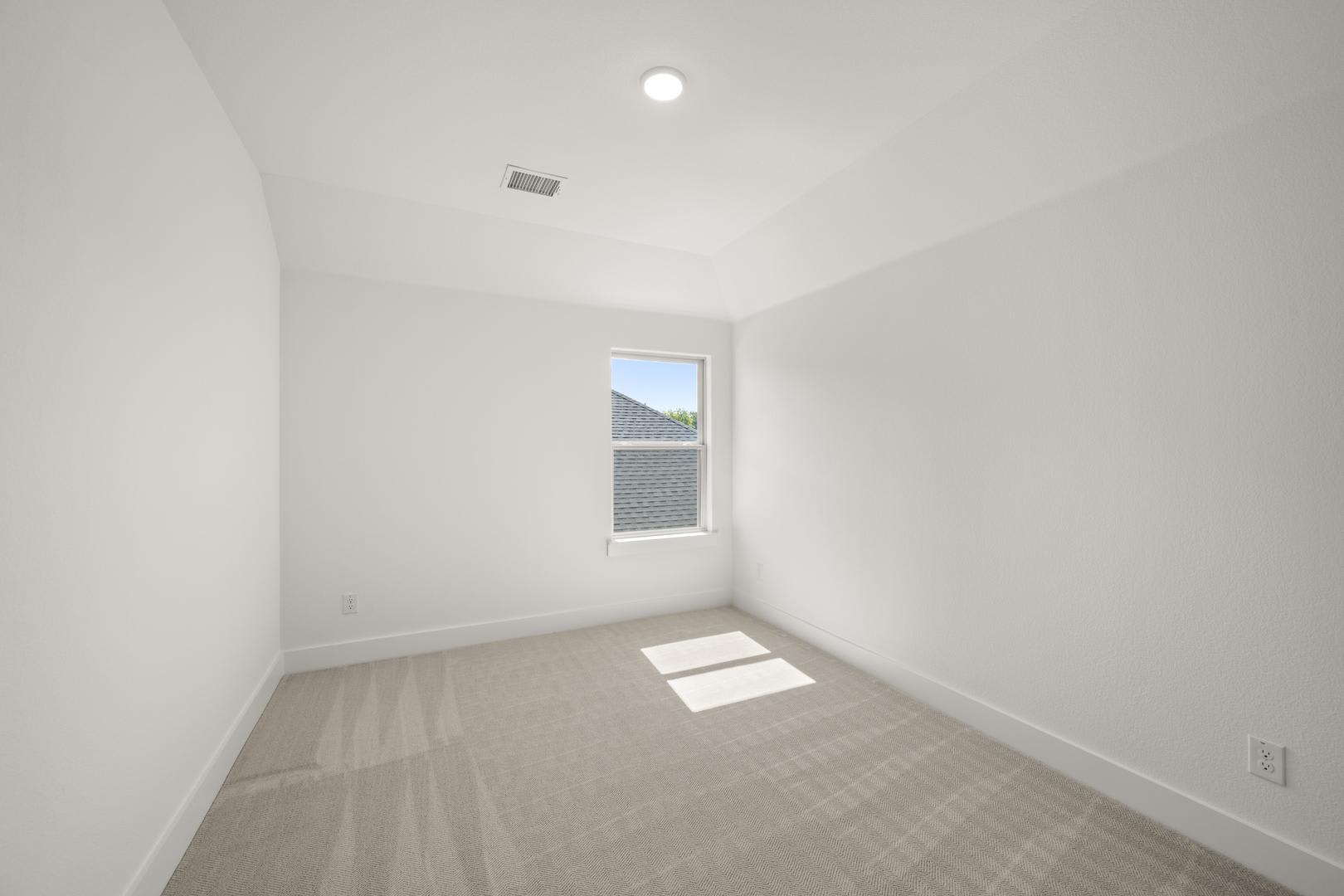 A bright, minimalist room with a single window, a plain white wall, and a hardwood floor.