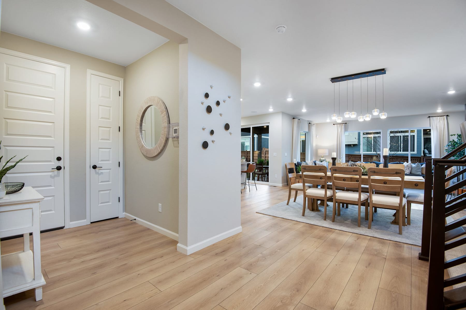 A bright and spacious open-concept living area with a dining table, wooden floors, and various decorative elements on the walls.