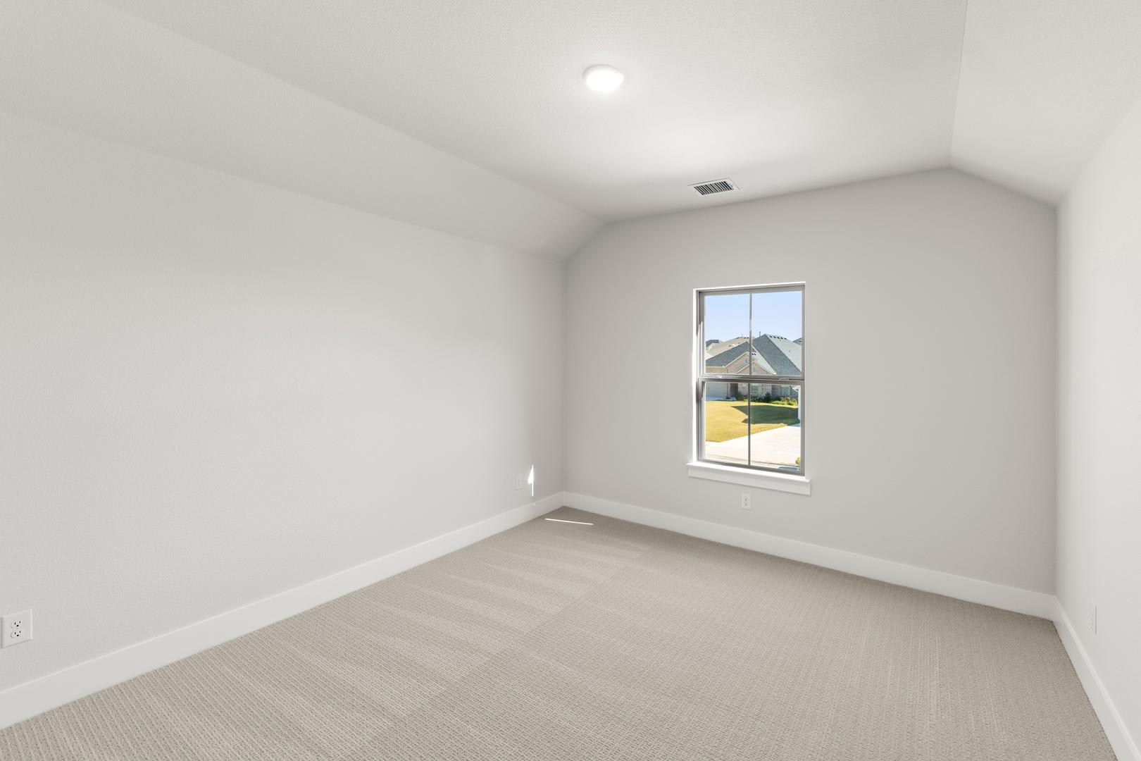 A bright, empty room with a window overlooking a grassy outdoor area.