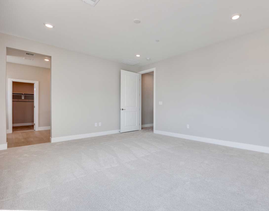 An empty, spacious room with white walls, a closet, and a hardwood floor.