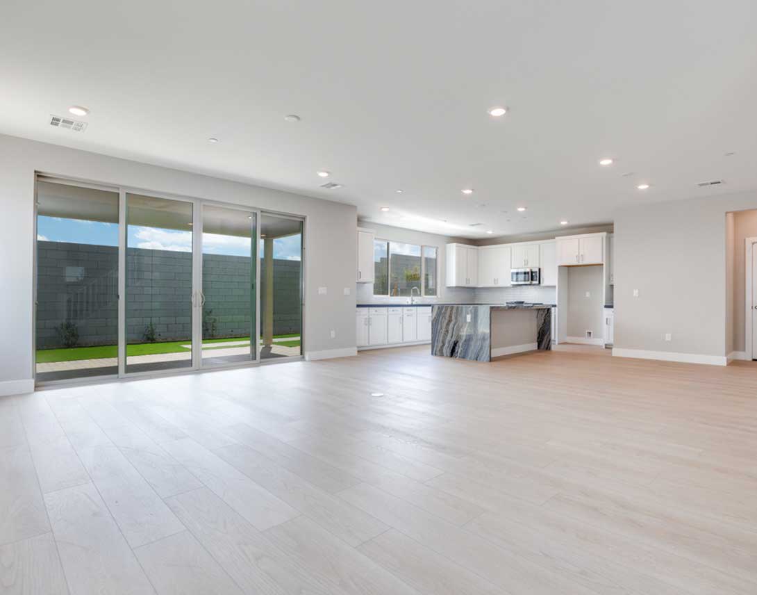 A spacious, open-concept living area with a modern kitchen, hardwood floors, and large sliding glass doors leading to an outdoor space.