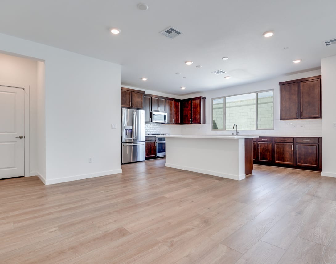 A spacious and modern kitchen with dark wood cabinets, stainless steel appliances, and a large open floor plan with hardwood floors.