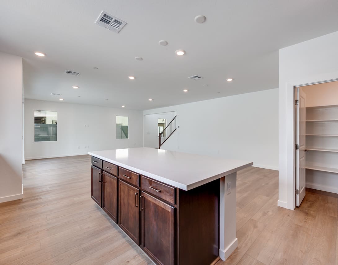 A modern kitchen with a large island countertop, dark wood cabinets, and a bright, open floor plan.