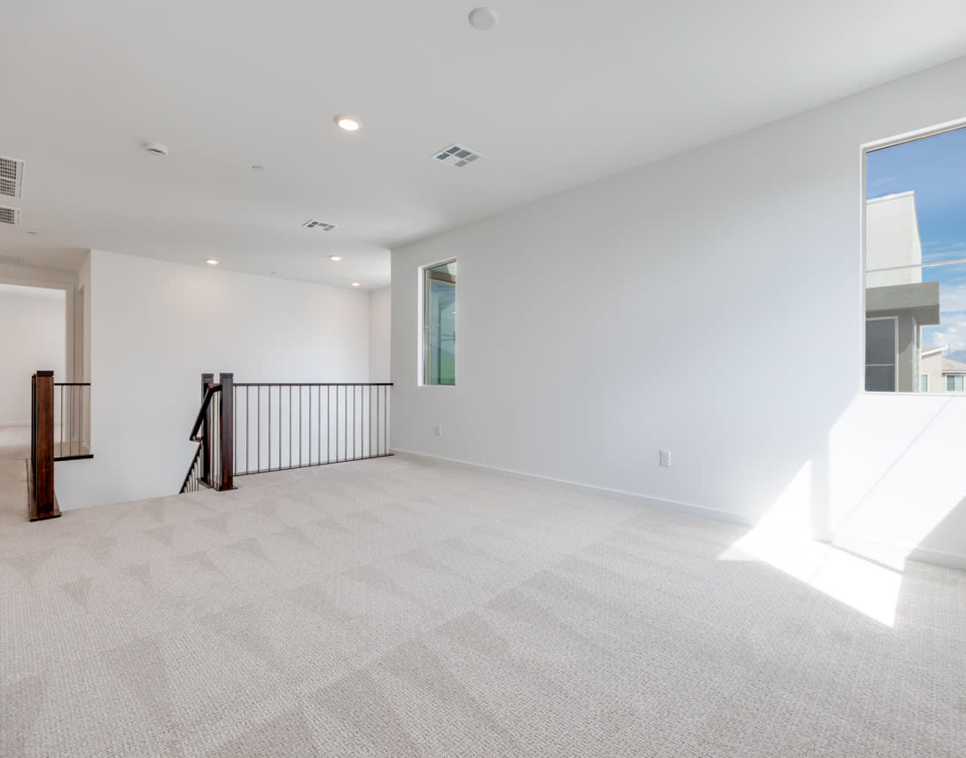 An empty, bright, and spacious room with a railing and a window, showcasing a minimalist and modern interior design.
