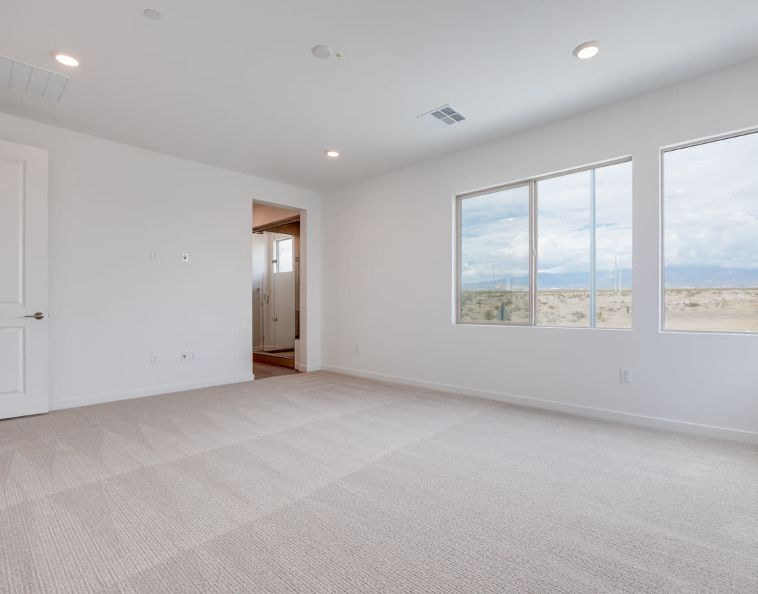 A spacious, well-lit room with large windows offering a scenic view of the outdoors, featuring a clean and minimalist interior design with hardwood flooring.