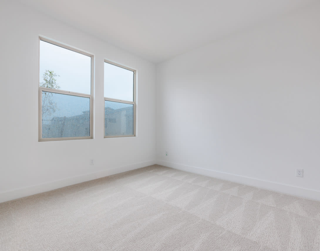A bright, minimalist room with large windows overlooking a scenic outdoor landscape.