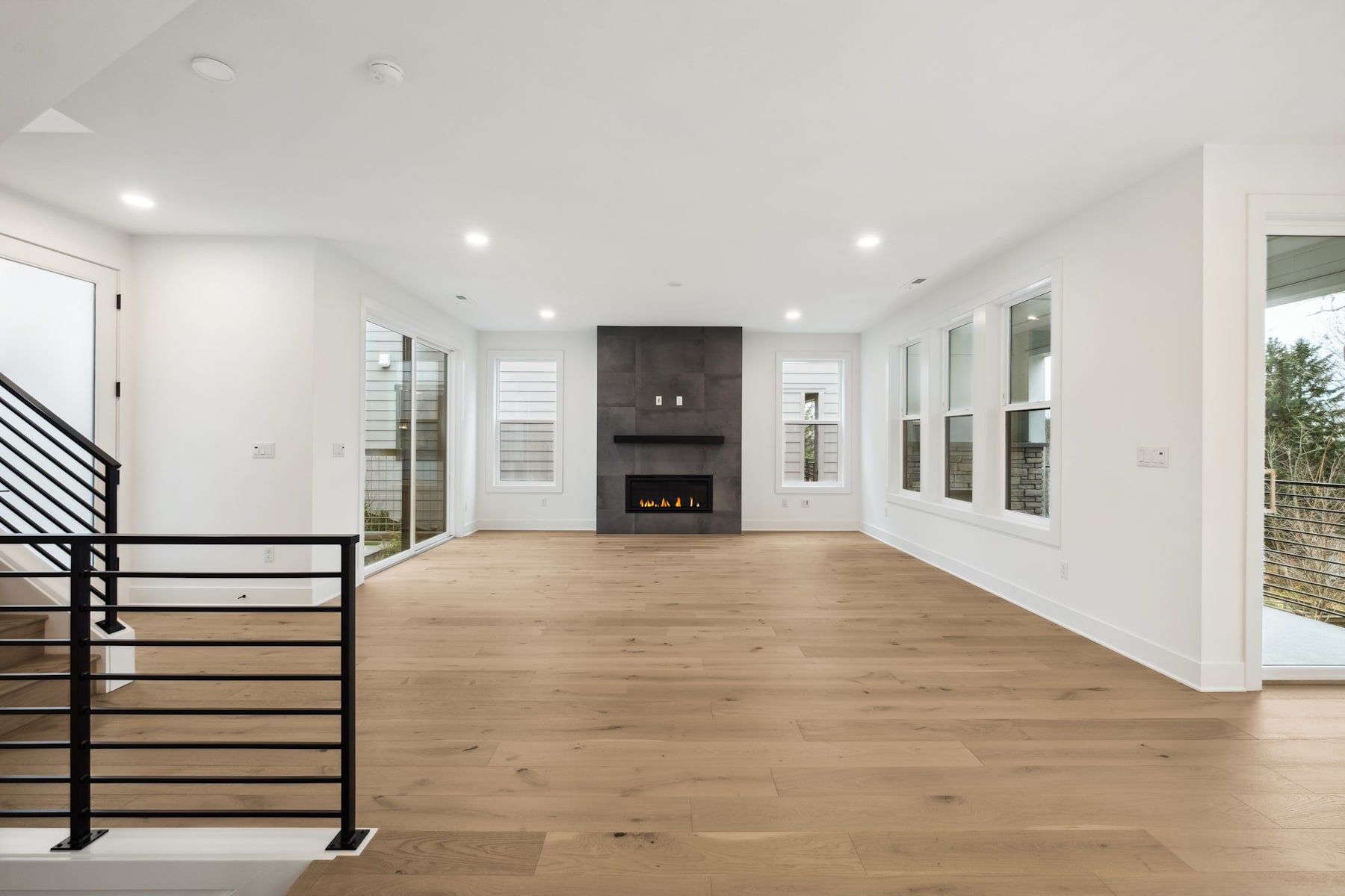 A spacious and modern interior with a fireplace, wooden flooring, and large windows providing ample natural light.