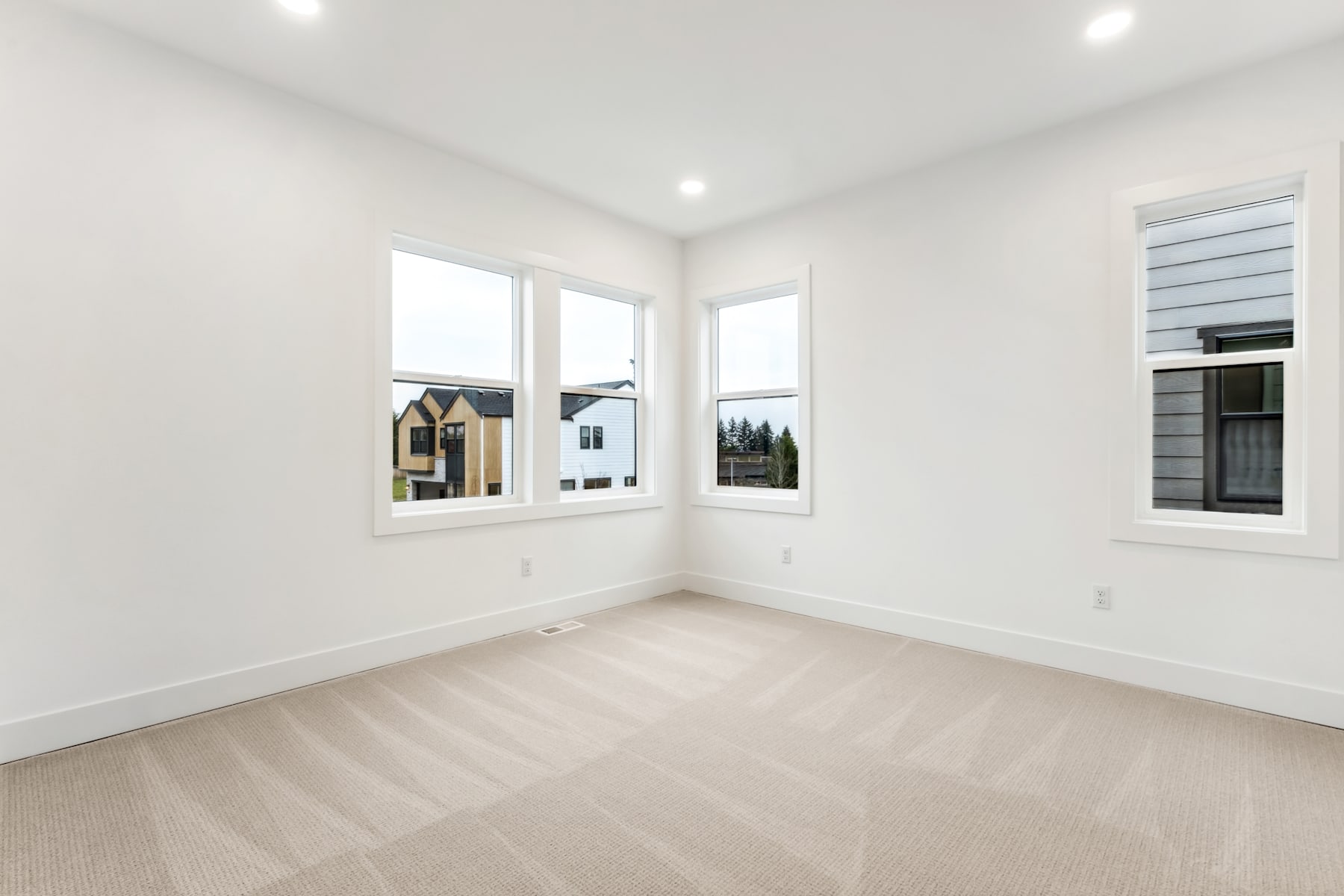 A bright, spacious room with large windows overlooking a scenic outdoor landscape, featuring a clean and minimalist interior design.