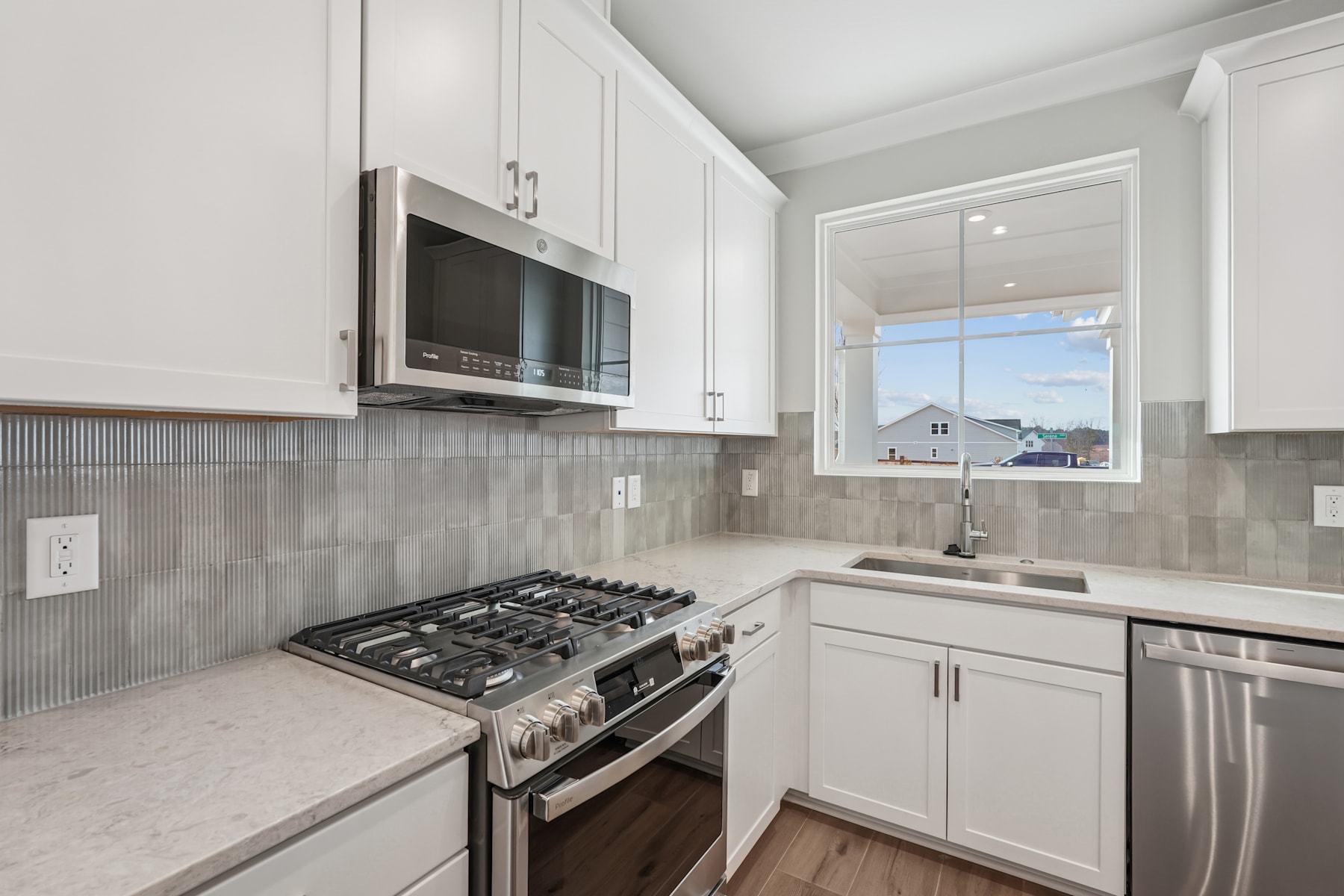 A modern, well-equipped kitchen with white cabinets, stainless steel appliances, and a tiled backsplash, set against a bright, airy backdrop.