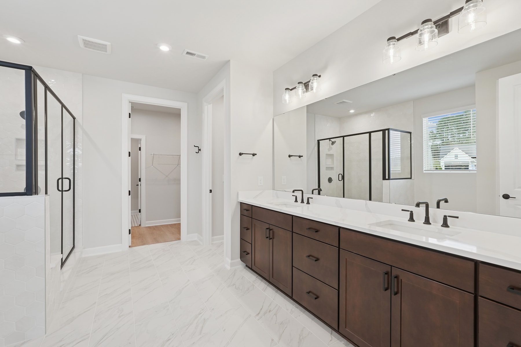 A modern and spacious bathroom with a double vanity, a glass shower enclosure, and a neutral color scheme.
