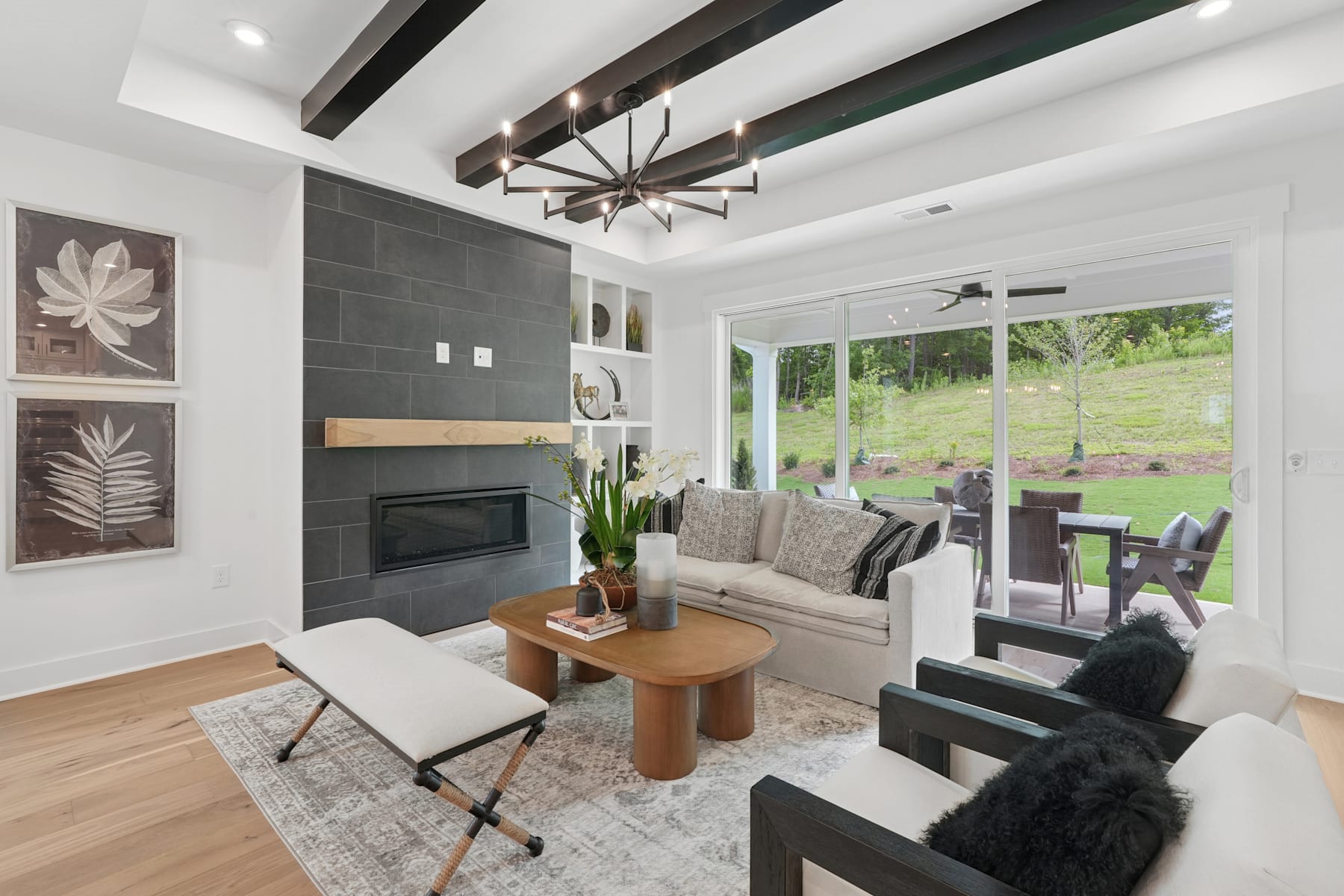 A modern and cozy living room with a fireplace, comfortable seating, and large windows overlooking a lush, green outdoor landscape.