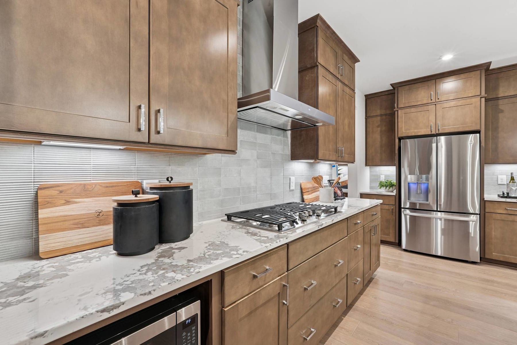 A modern and well-equipped kitchen with wooden cabinets, stainless steel appliances, and a marble countertop.