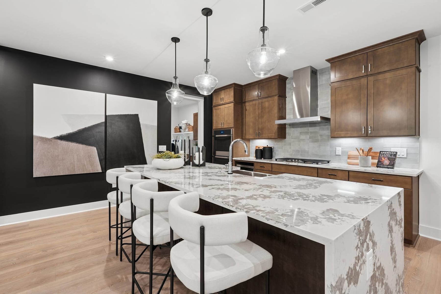 A modern and stylish kitchen with wooden cabinets, a marble-topped island, and pendant lights creating a warm and inviting atmosphere.