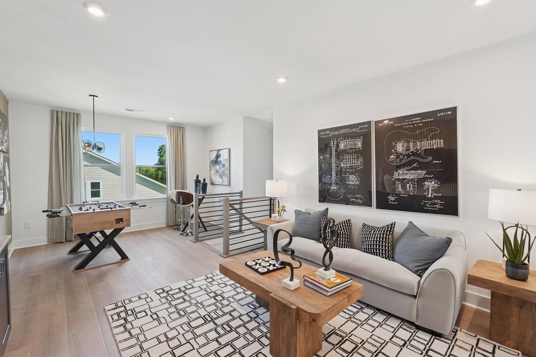 A modern and stylish living room with a couch, coffee table, and artwork on the walls, set against a backdrop of large windows and natural light.