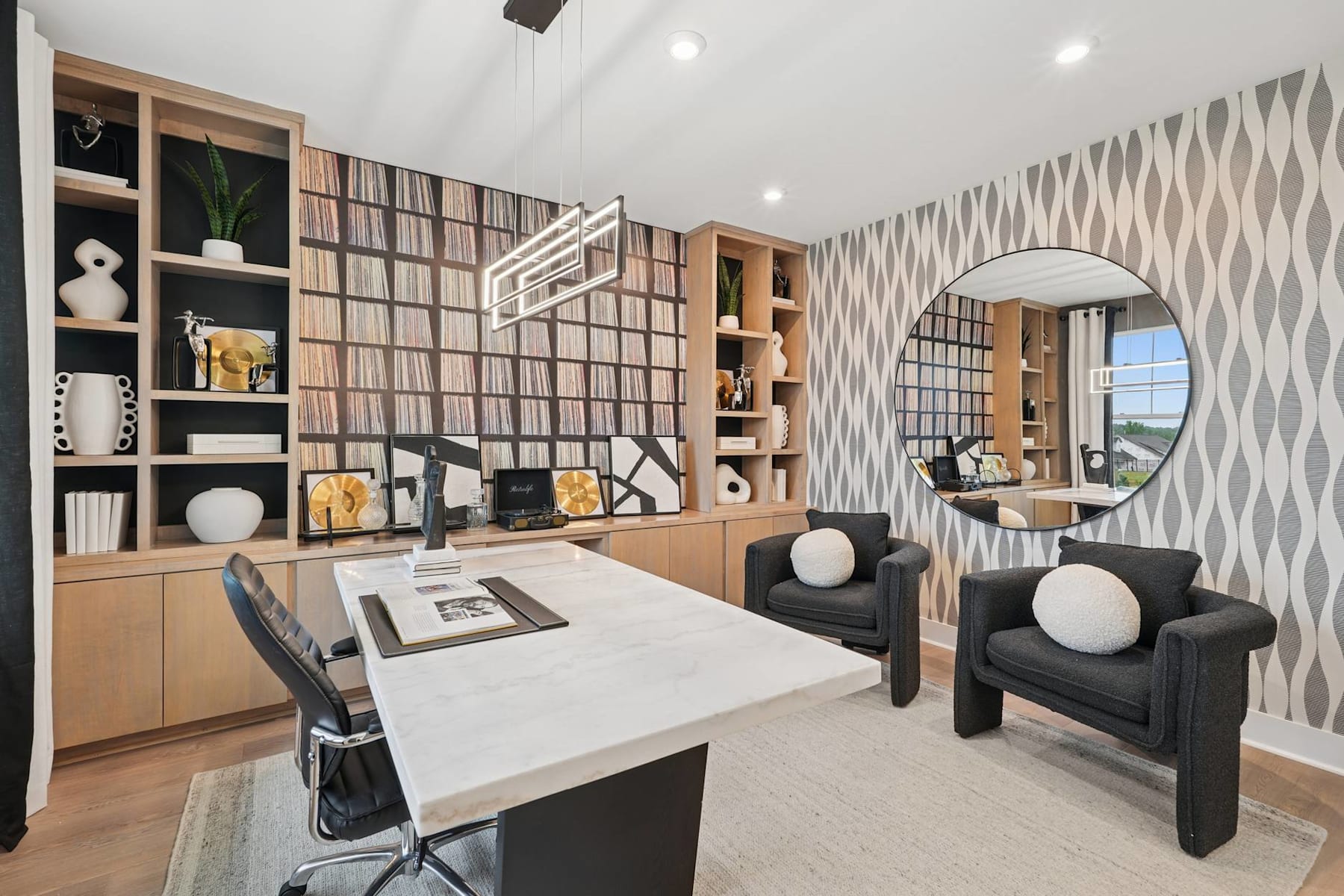 A modern and stylish home office space with built-in shelving, a large desk, and comfortable seating, set against a patterned accent wall.